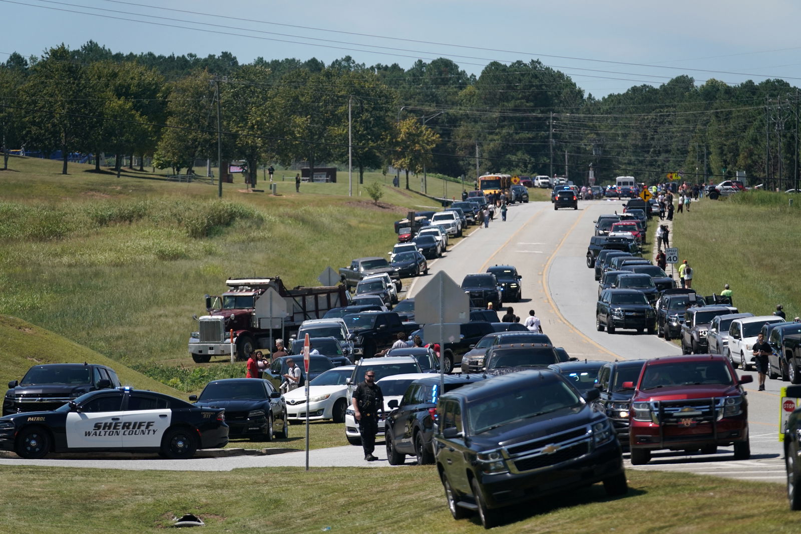 Cars are parked on the sides of a road as law enforcement officers work at the scene of a shooting at Apalachee High School in Winder, Georgia, Sept. 4, 2024.
