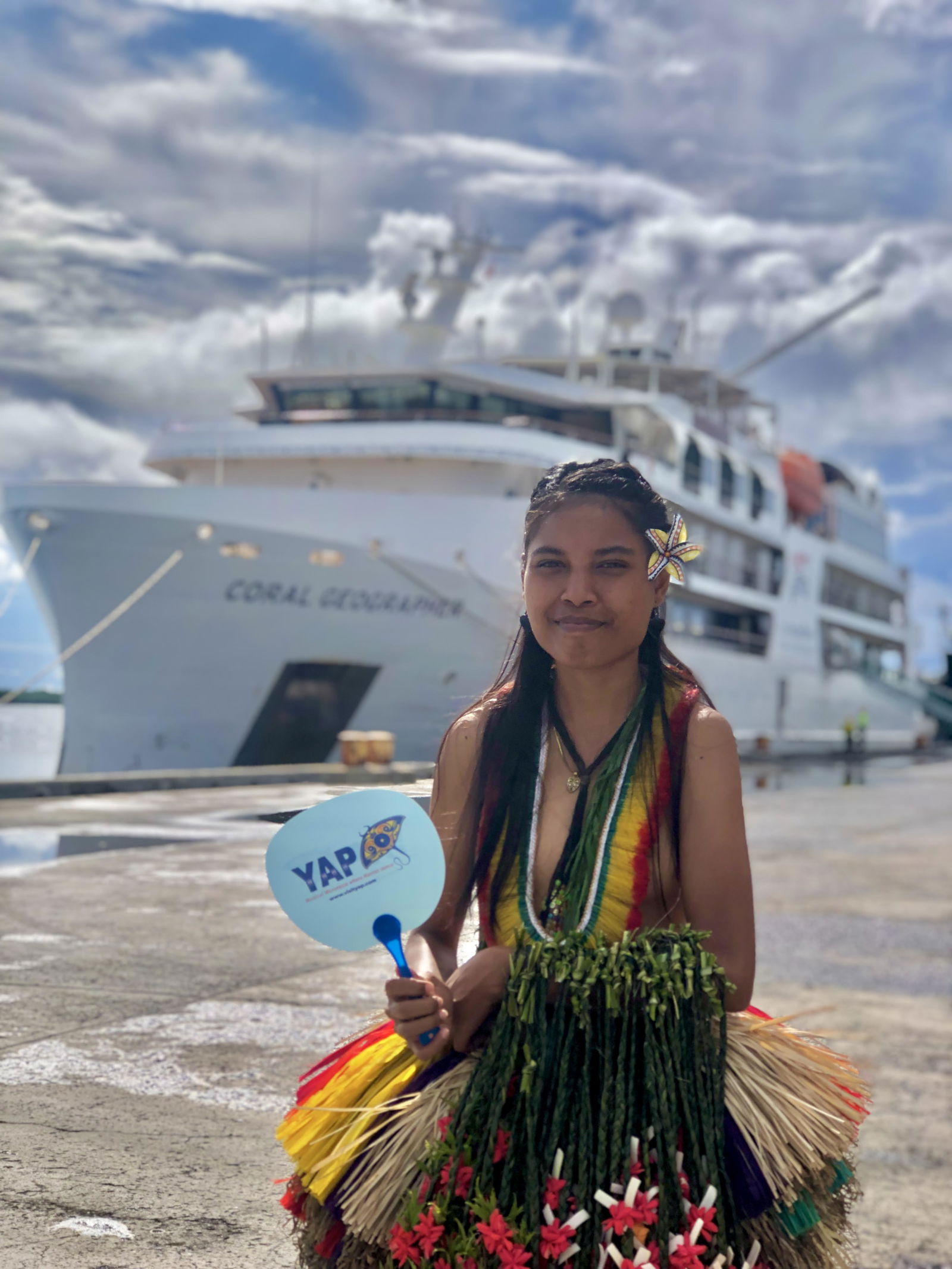 A greeter for the Coral Geographer cruise visit poses for a photo.