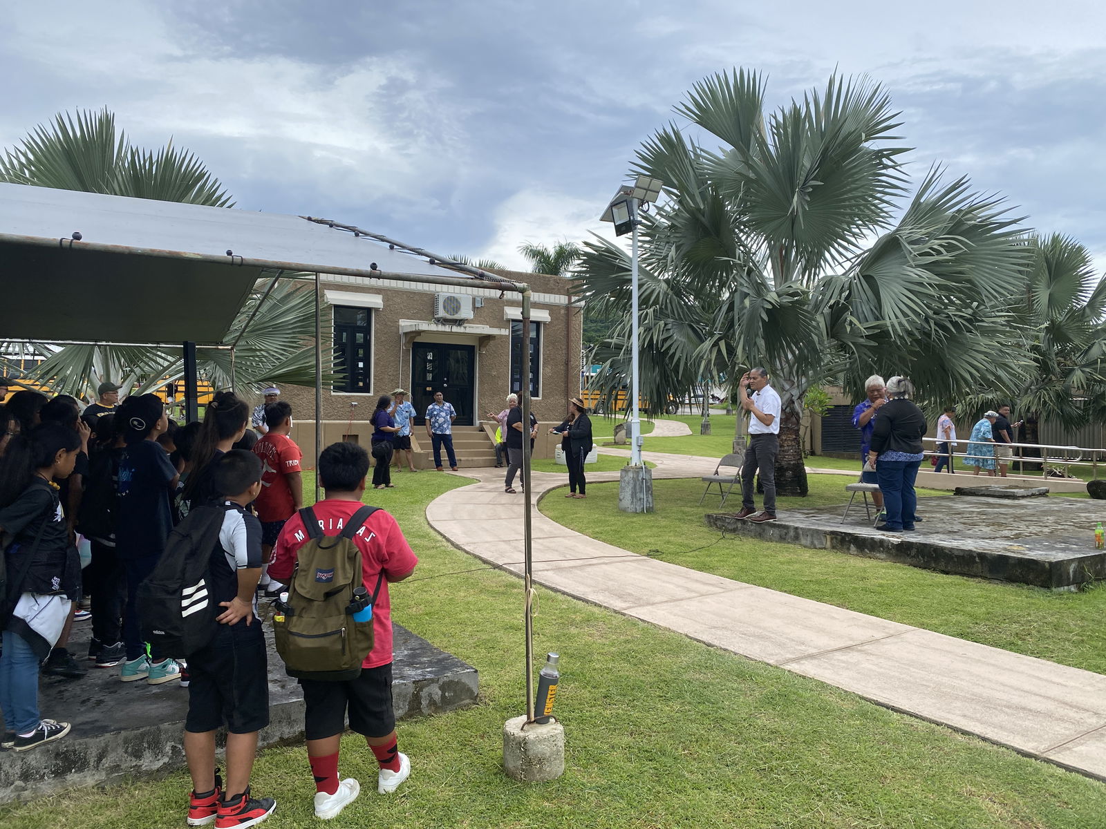 NMI Museum of History and Culture’s Lenny Leon, holding a microphone, speaks to students about the Cultural Roadmap program.  