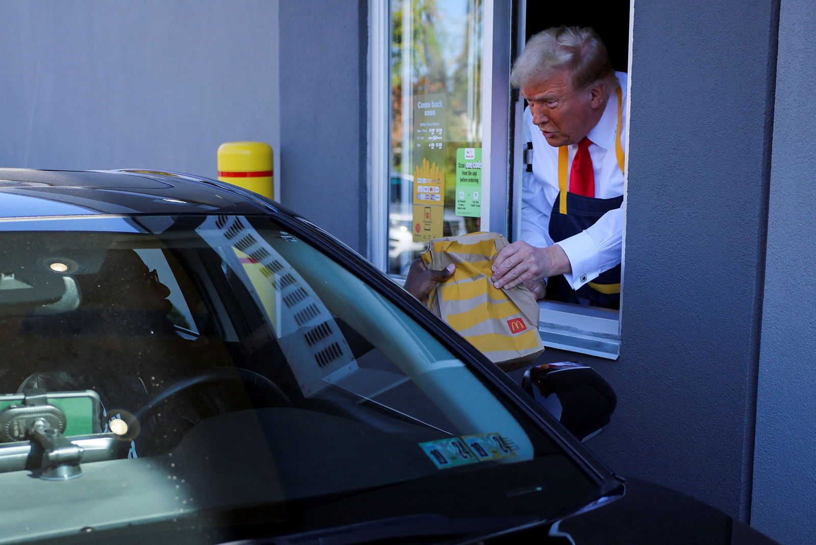 Republican presidential candidate Donald Trump hands french fries to a customer through the drive-through window of a McDonald’s in suburban Philadelphia on Oct. 20, 2024.