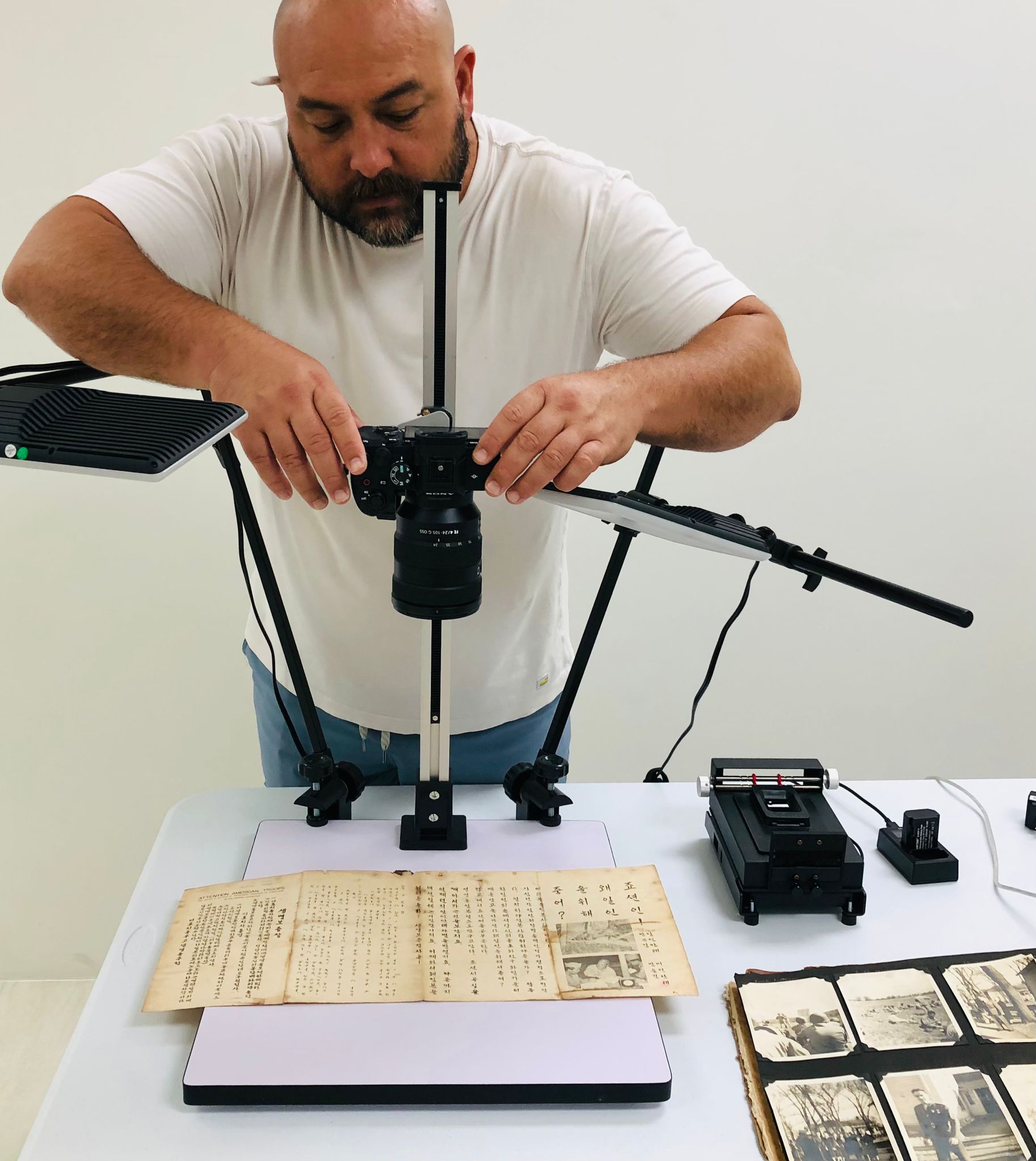 Roberto Santos, archives manager at the Humanities Council, photographs a document from World War II to preserve in the council's digital archives.