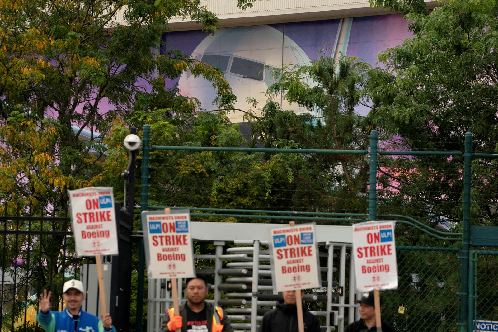 The image of a Boeing 737 jetliner is seen behind Boeing factory workers and supporters as they gather on a picket line near the entrance to a Boeing production facility in Renton, Washington,  Sept. 15, 2024.