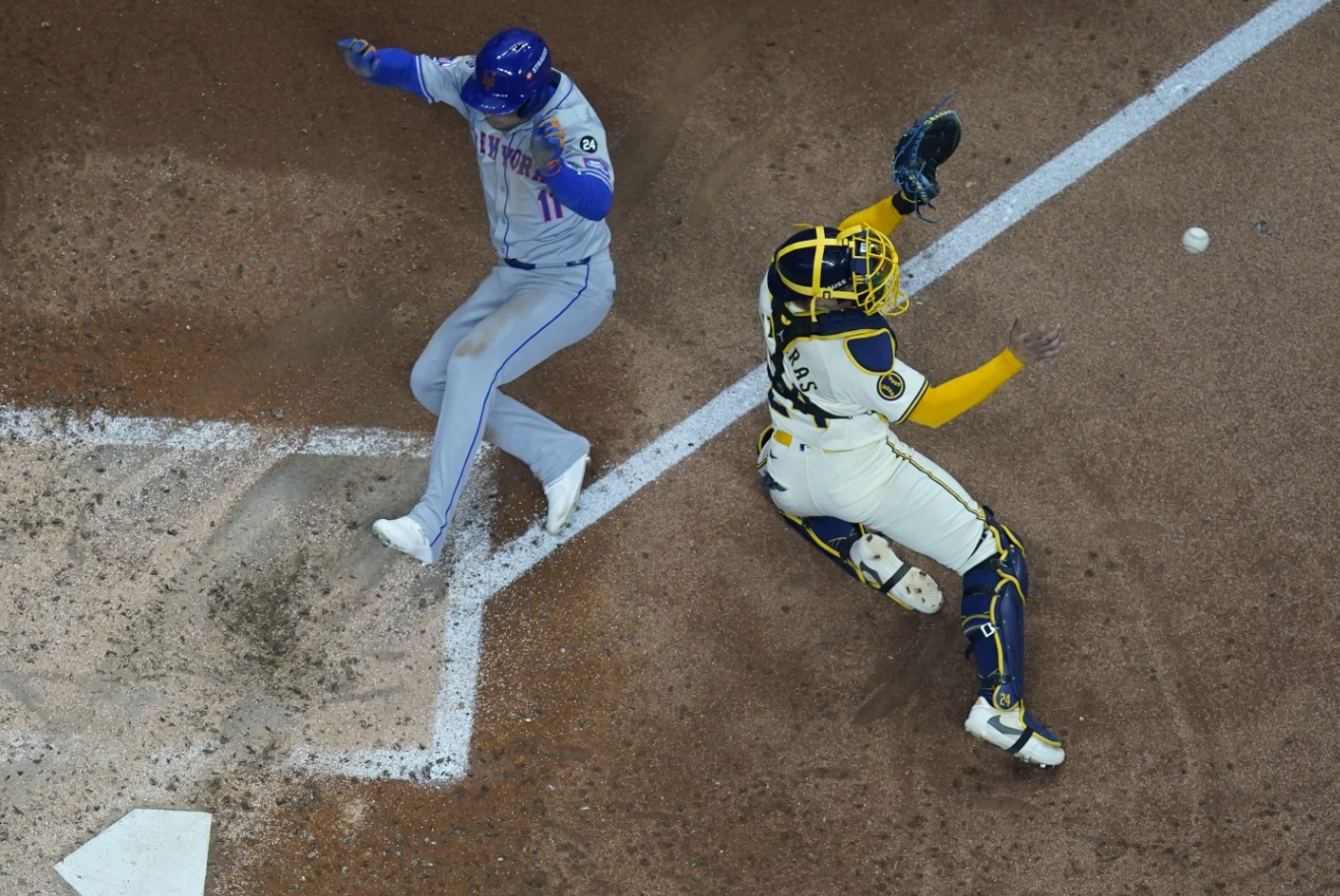 New York Mets’ Jose Iglesias scores past Milwaukee Brewers catcher William Contreras during the fifth inning of Game 2 of a National League wild card game Tuesday, Oct. 1, 2024 in Milwaukee.