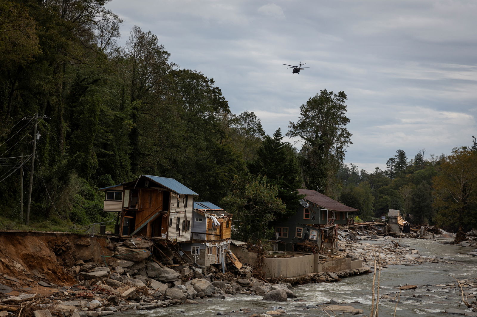 A helicopter flies near damaged buildings following the passing of Hurricane Helene, in Bat Cave, North Carolina, Sept. 30, 2024.