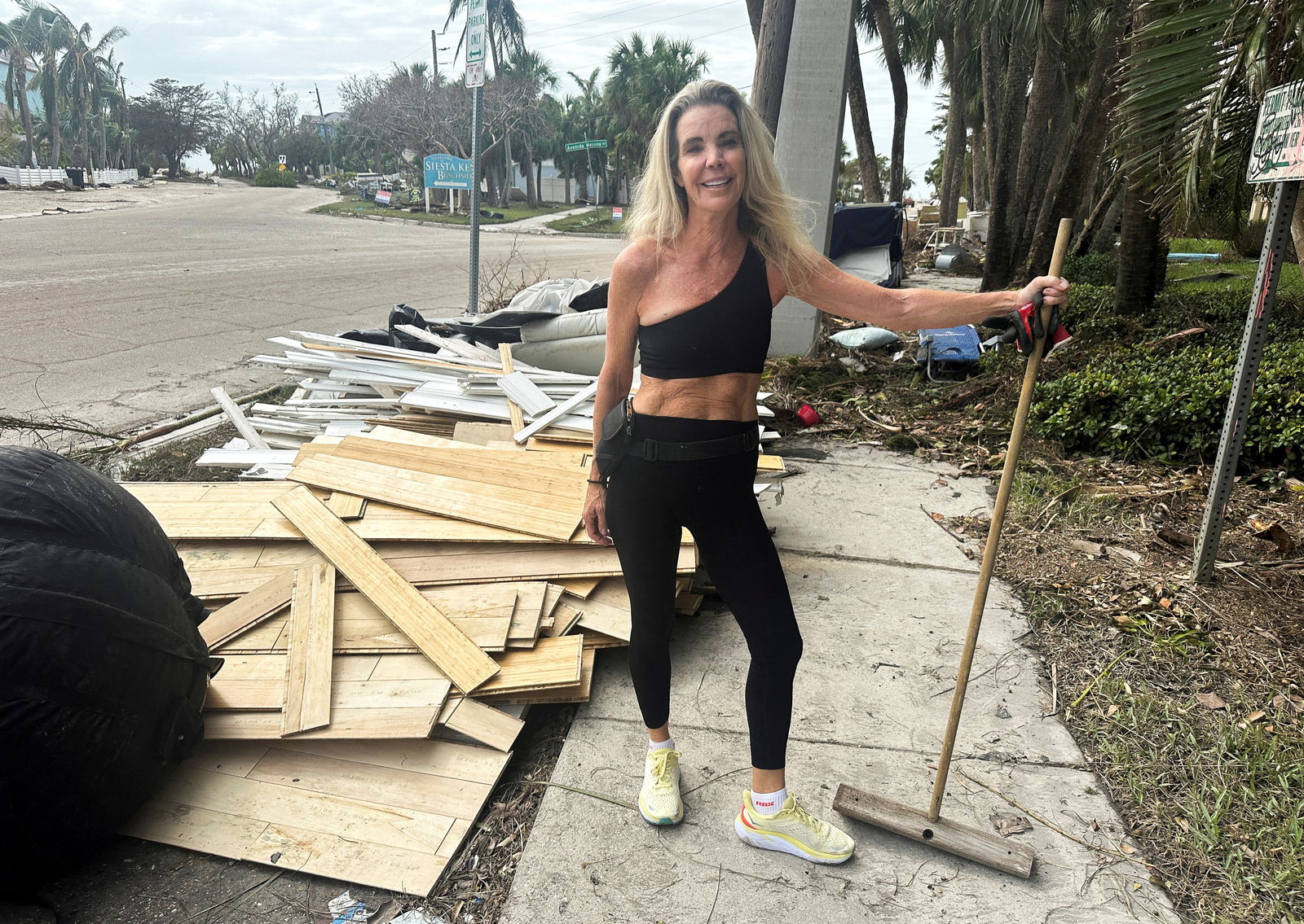 Chris Fiore poses for a photo amid debris near her damaged house, following Hurricane Milton's landfall, in Siesta Key, Florida, Oct. 11, 2024.
