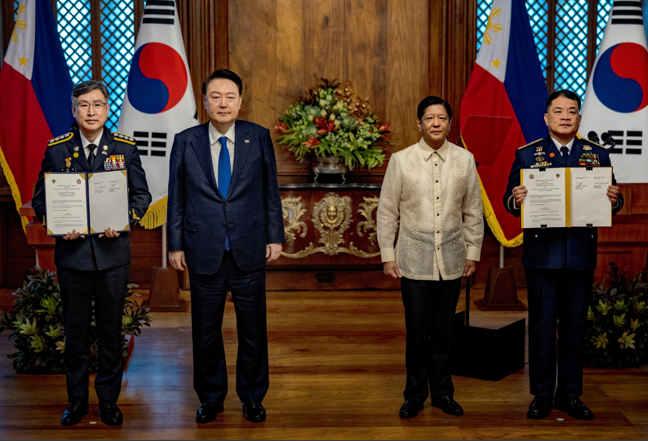 Philippine President Ferdinand Marcos Jr. and his South Korean counterpart Yoon Suk Yeol pose for pictures as Kim Jong-Uk, commissioner general of the Korea Coast Guard, and Ronnie Gil Gavan, commandant of the Philippine Coast Guard, hold up signed agreements during a meeting at the Malacañang presidential palace in Manila, the Philippines, Oct. 7, 2024.