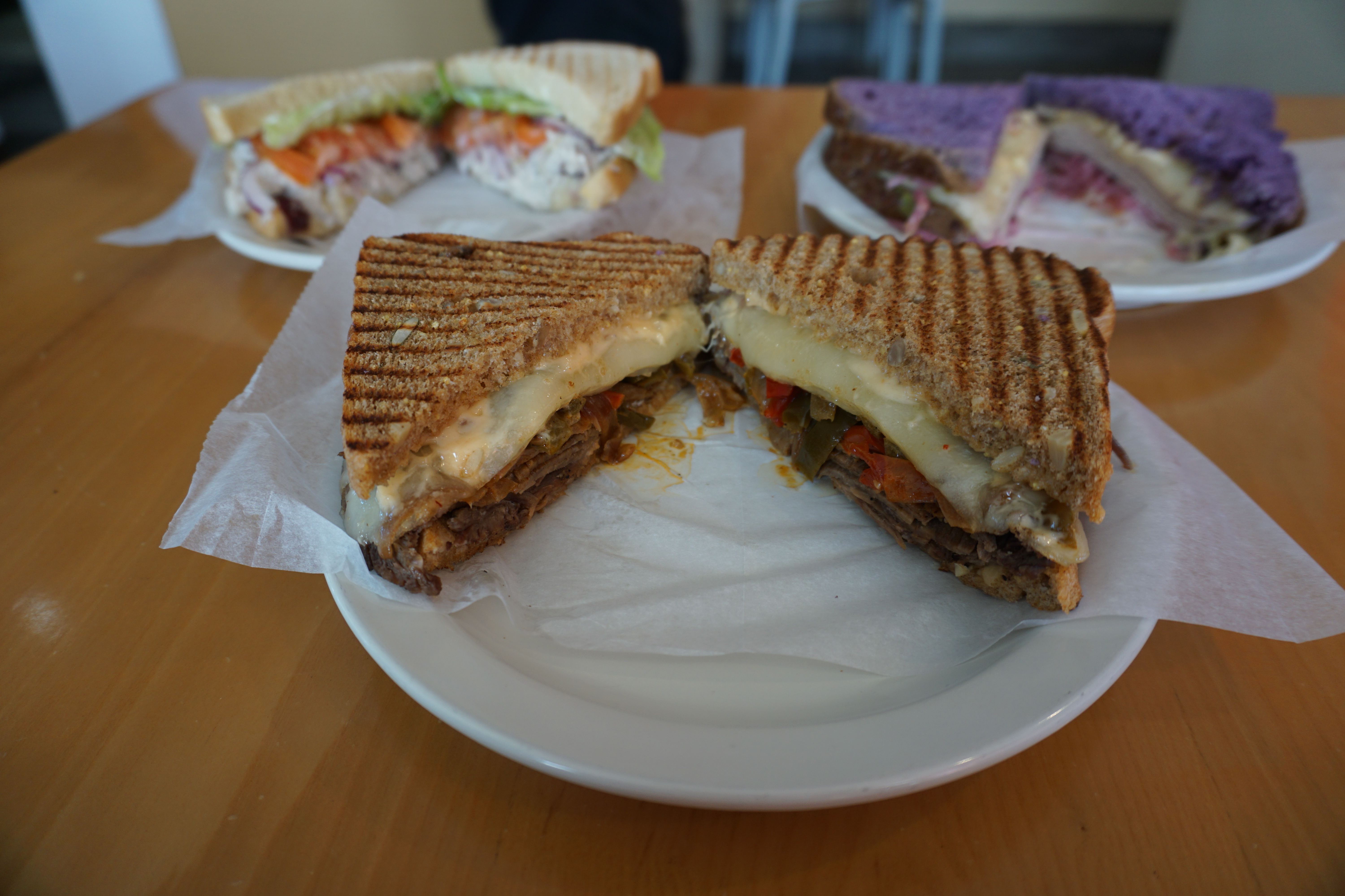 The Roasted Pepper Chipotle Cheesesteak is one hearty sandwich made with roast beef, Swiss cheese, marinated roasted bell pepper and onions, and chipotle mayonnaise. Behind it are the Big Sky Chicken Salad on the left, and the Baja Chipotle Turkey. 