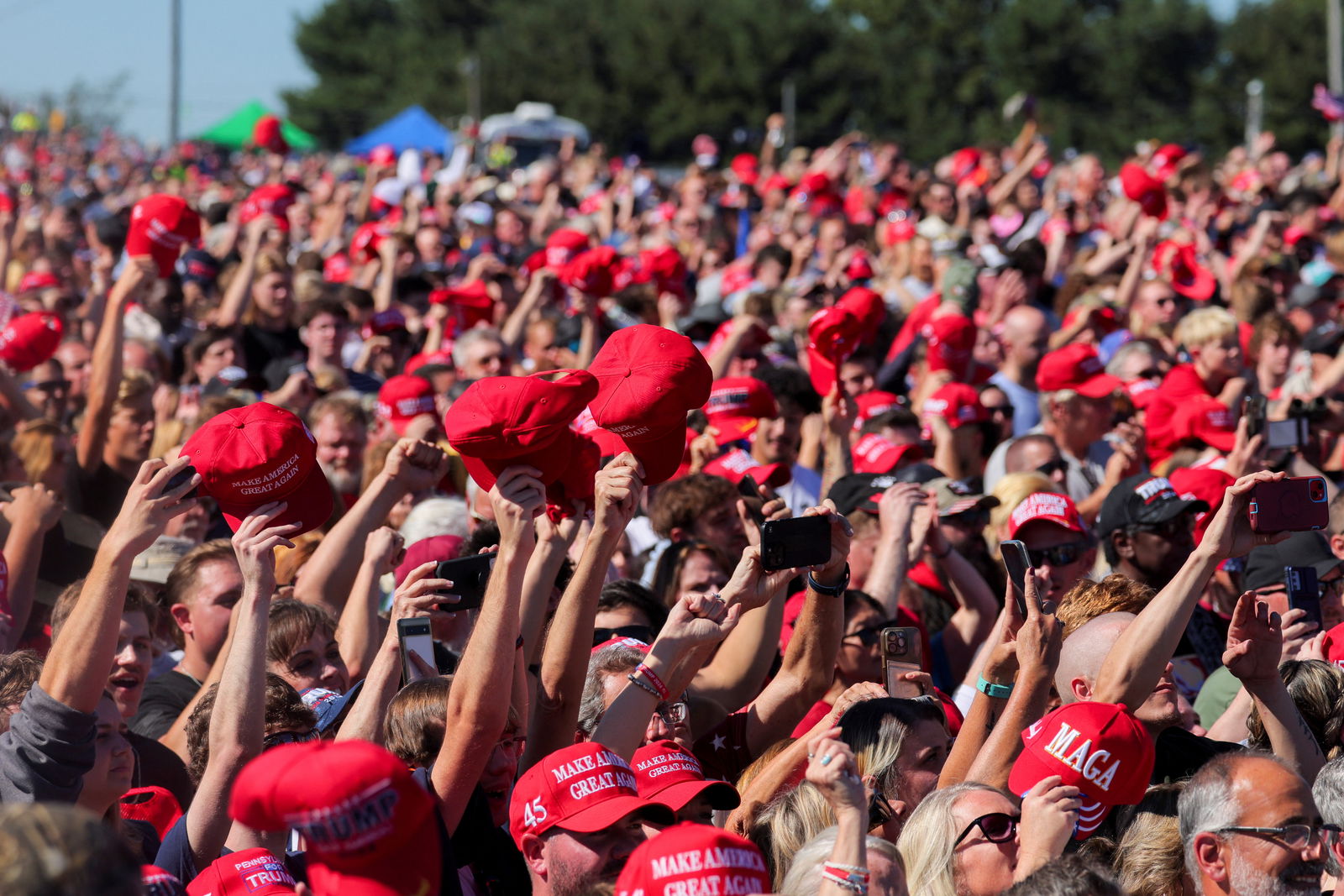 Supporters of Republican presidential nominee Donald Trump raise MAGA hats, on the day Trump returns for a rally at the site of the July assassination attempt against him, in Butler, Pennsylvania, Oct. 5, 2024.
