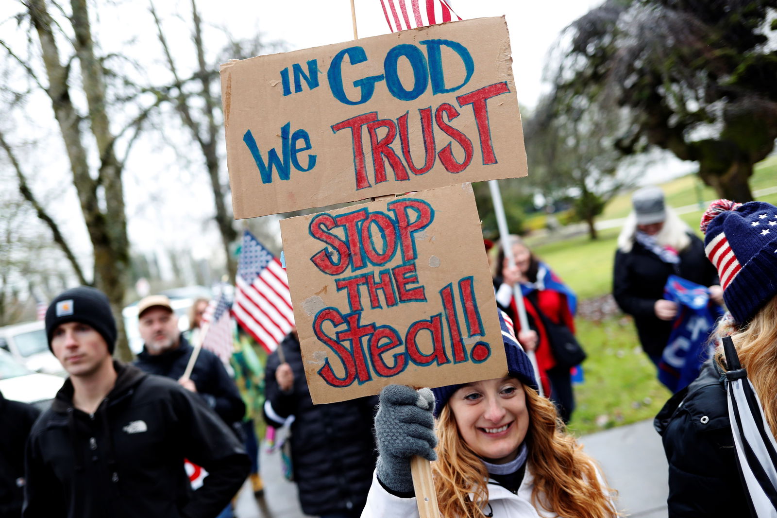 A protester holds signs saying "In God we trust" and "Stop the Steal!" at a rally in support of President Donald Trump at the Oregon State Capitol in Salem, Oregon, Jan. 6, 2021.