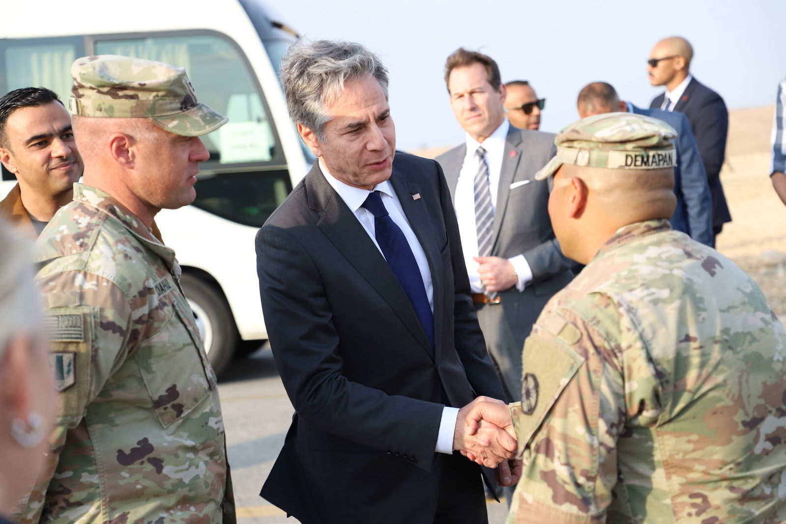 U.S. Army Major John Paul A. Demapan, right, back to the camera, shakes hands with U.S. Secretary of State Antony Blinken at a foreign humanitarian aid security screening site in Jordan.