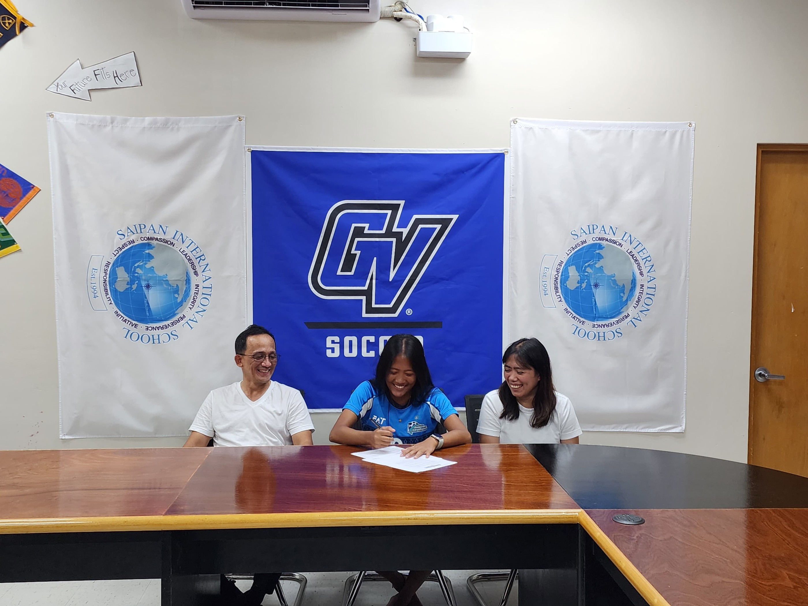 Andrei Kaithlyn Chavez smiles with her parents, Jov and Magie, as she signs with Grand Valley State University at Saipan International School on Friday.