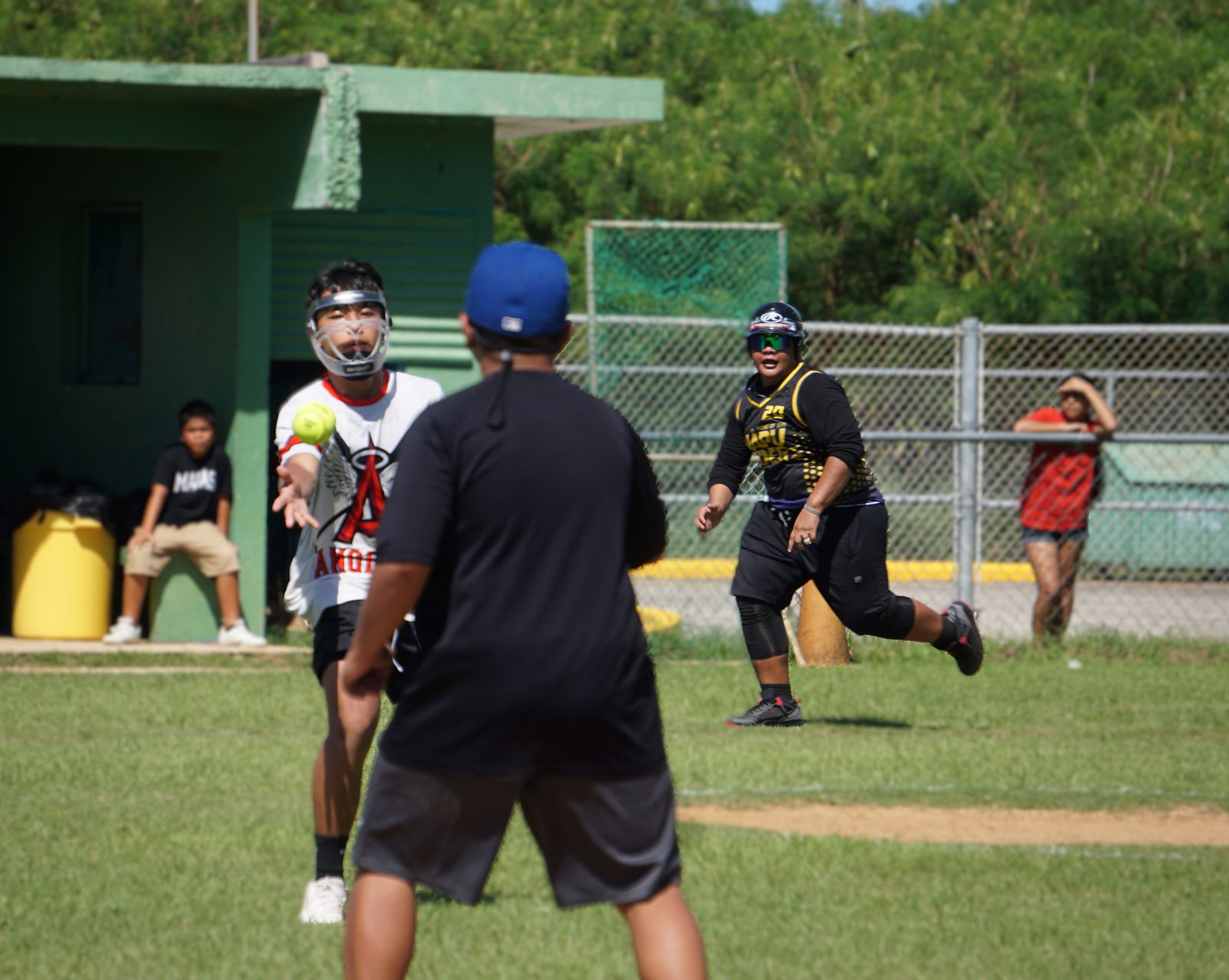 Mount Carmel School pitcher Leighton Tomokane-Tenorio tosses the ball to first base for the pickoff while a Francisco M. Sablan Middle School runner steals home during a boys middle school division game of the PSS-SBL Interscholastic Fastpitch Softball League SY24-25 at the Dandan softball field on Saturday.