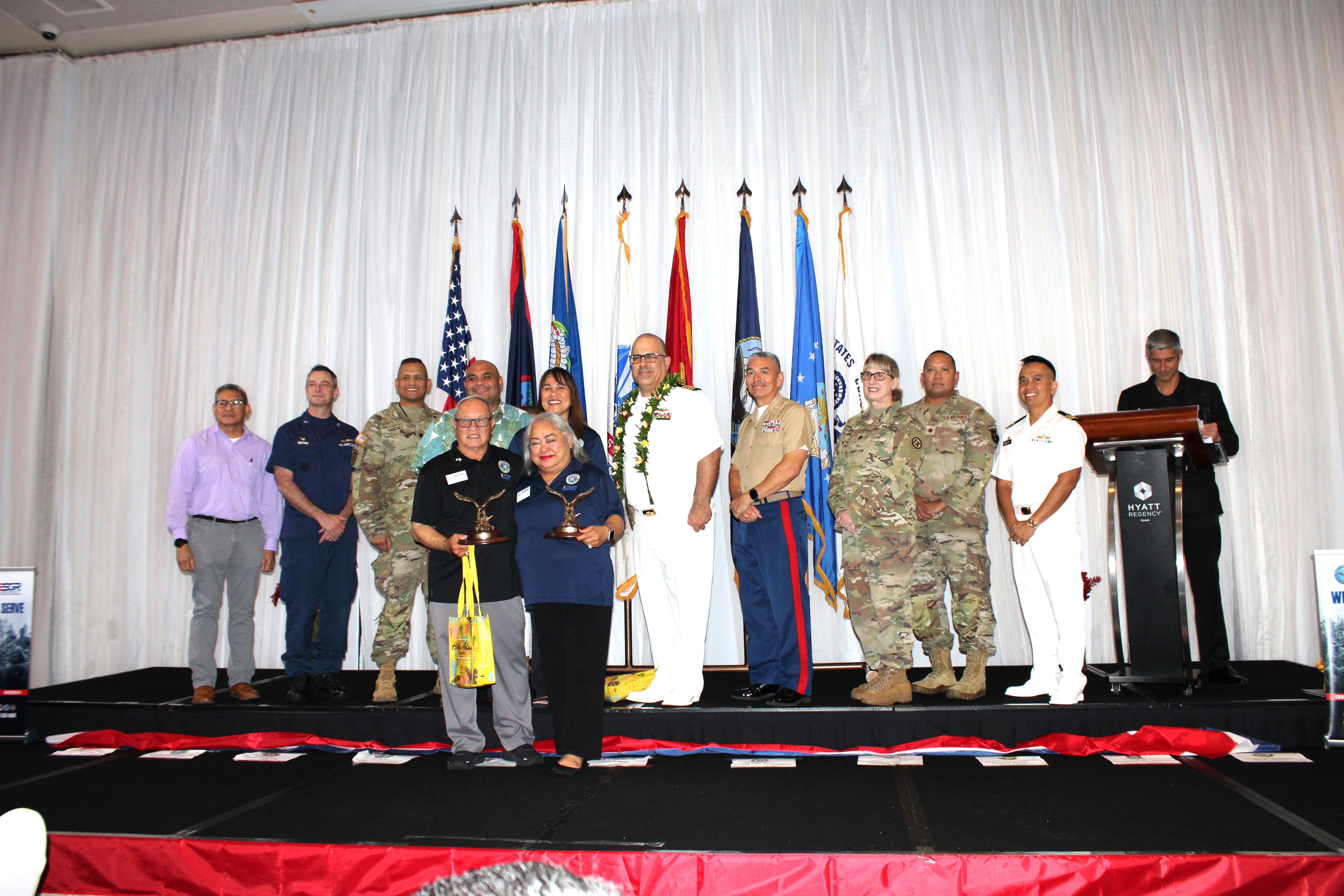 2024 Spirit of Volunteerism Awarded to Retired U.S. Army Major General Benny M. Paulino, GU-CNMI Vice Chair, and 2023 Spirit of Volunteerism Awarded to Dina San Nicolas, GU-CNMI Training Director, since the award was not presented last year. Front, from left: Retired U.S. Army Major General Benny M. Paulino, GU-CNMI Vice Chair, and Dina San Nicolas, GU-CNMI Training Director. Back, from left: Lieutenant Colonel Victor Balajadia, Director of Staff, Guam Air National Guard; Captain Robert Kistner, U.S. Coast Guard; Lieutenant Colonel Romeo Sanchez, 1st-294th Infantry Battalion, Guam Army National Guard: Acting Governor Joshua Tenorio; CathyAnn C. Gogue, GU-CNMI State Chair; U.S. Navy Captain Craig S. Der Ananian, Navy Readiness and Mobilization Command, San Diego; Colonel Ernest Govea, Commanding Officer, Marine Corps Base Camp Blaz, U.S. Marine Corp.; Lieutenant Colonel Penny Sima, U.S. Army Reserve; Major Benjamin Guerrero, U.S. Air Force Reserve; and Lieutenant Commander Brian Matic, U.S. Navy Reserve.