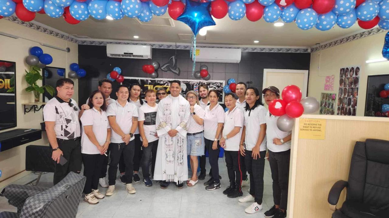 Jigz Barbershop & Beauty Salon President Jigg Hernando, fourth left, Father Arman Hagos, center, pose for a photo with the staff during the opening of a new branch in Garapan on Friday.