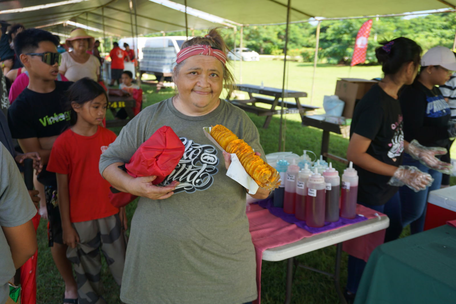 A resident poses with her fried potatoes courtesy of Herman's Modern Bakery during its Family Fun Day event on Saturday.