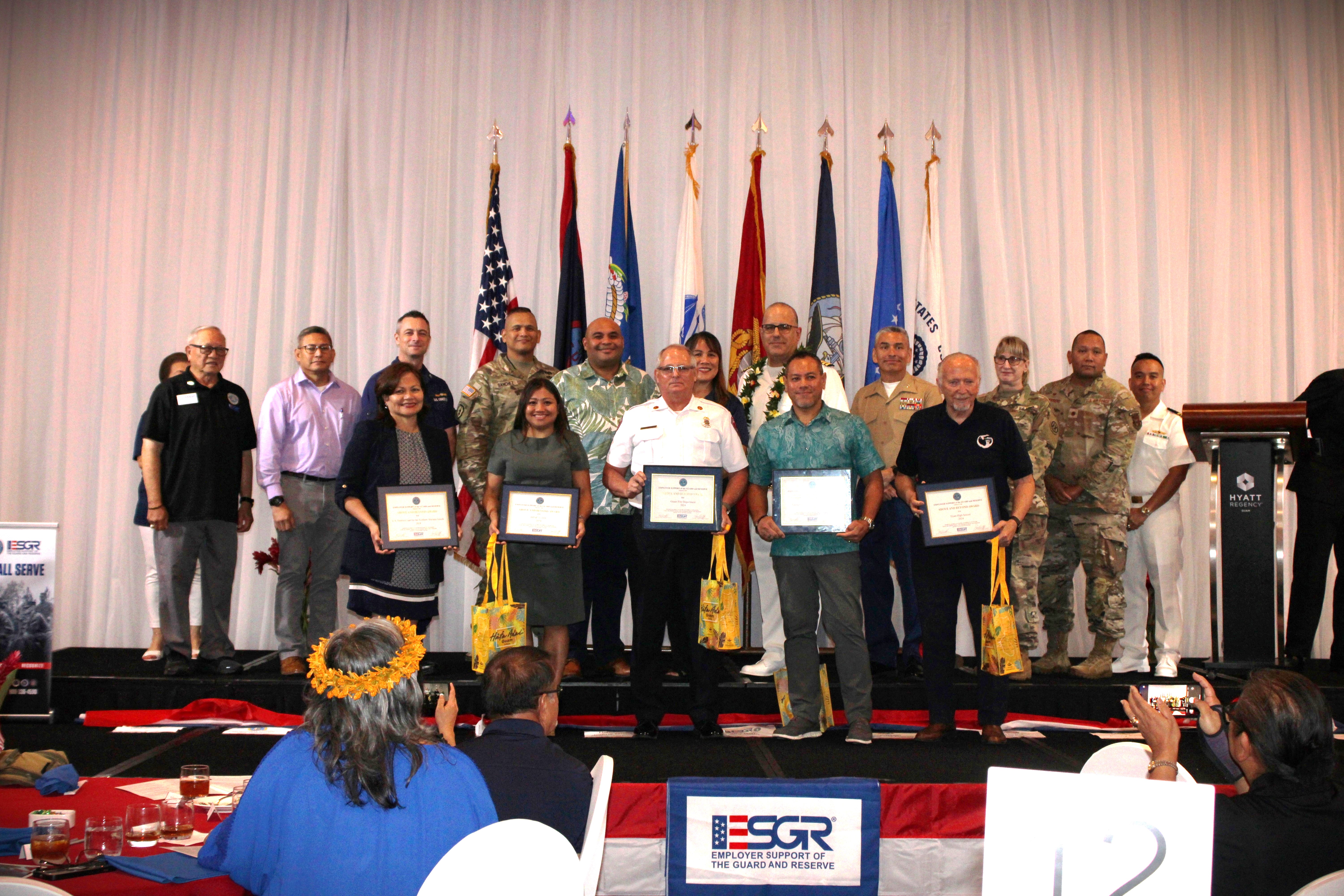 Seven companies received the Above and Beyond Award. Front, from left: Chief Judge Ramona Manglona, U.S. District Court for the Northern Mariana Islands; Sheila Concepcion, Business Director, DZSP-21, LLC; Assistant Fire Chief Darren Burrier, Guam Fire Department; Jorge Guerrero, Assistant Federal Security Director, Transportation Security Administration; Dr. Erik Swanson, Superintendent, Guam Department of Education, receiving for Tiyan High School. Back, from left: Retired U.S. Army Major General Benny M. Paulino, GU-CNMI Vice Chair; Lieutenant Colonel Victor Balajadia, Director of Staff, Guam Air National Guard; Captain Robert Kistner, U.S. Coast Guard; Lieutenant Colonel Romeo Sanchez, 1st-294th Infantry Battalion, Guam Army National Guard: Acting Governor Joshua Tenorio; CathyAnn C. Gogue, GU-CNMI State Chair, U.S. Navy Captain Craig S. Der Ananian, Navy Readiness and Mobilization Command, San Diego; Colonel Ernest Govea, Commanding Officer, Marine Corps Base Camp Blaz, U.S. Marine Corp.; Lieutenant Colonel Penny Sima, U.S. Army Reserve; Major Benjamin Guerrero, U.S. Air Force Reserve; and Lieutenant Commander Brian Matic, U.S. Navy Reserve.