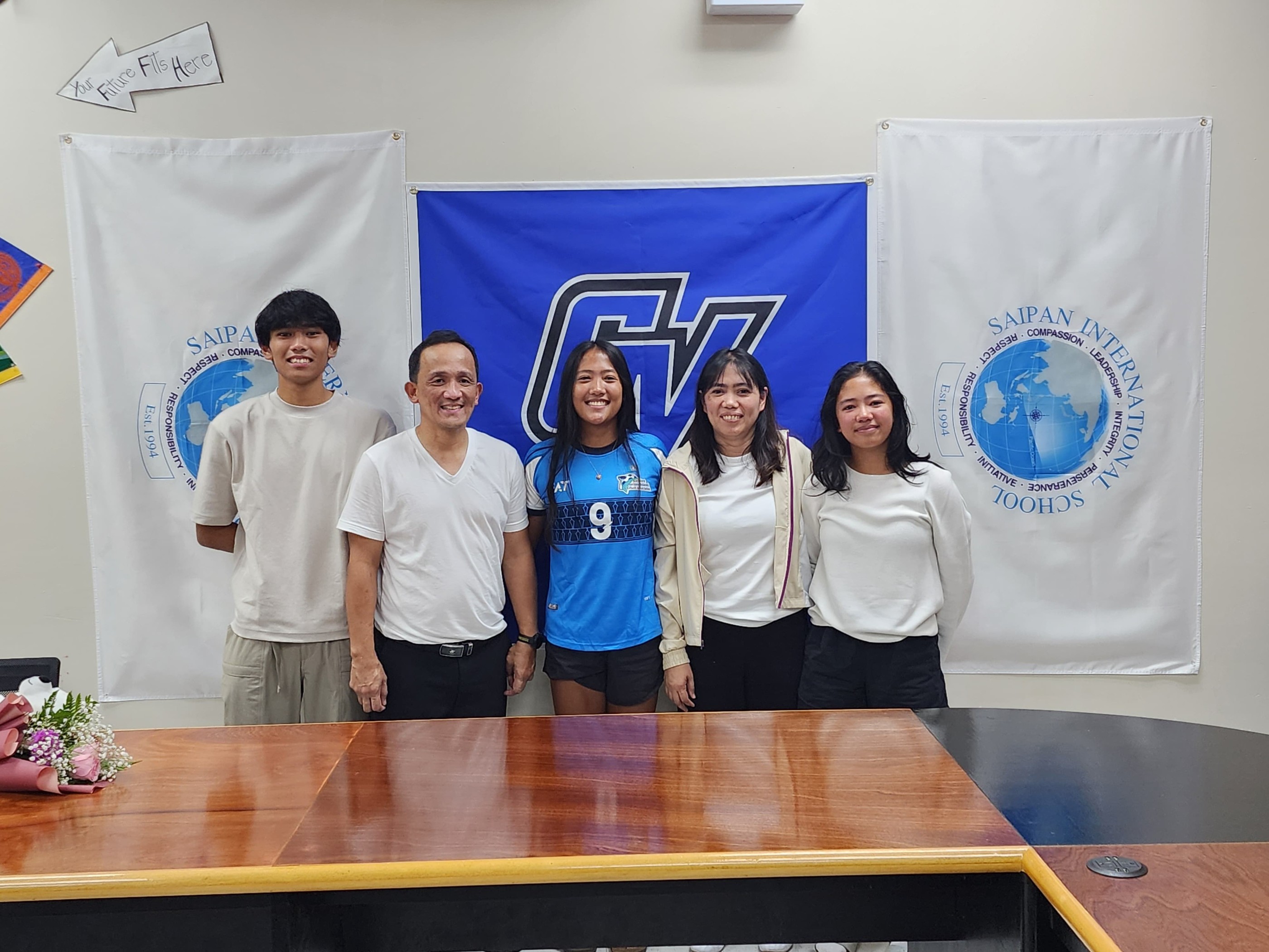 Andrei Kaithlyn Chavez and her family pose for a group photo during a signing ceremony with Grand Valley State University at Saipan International School on Friday.
