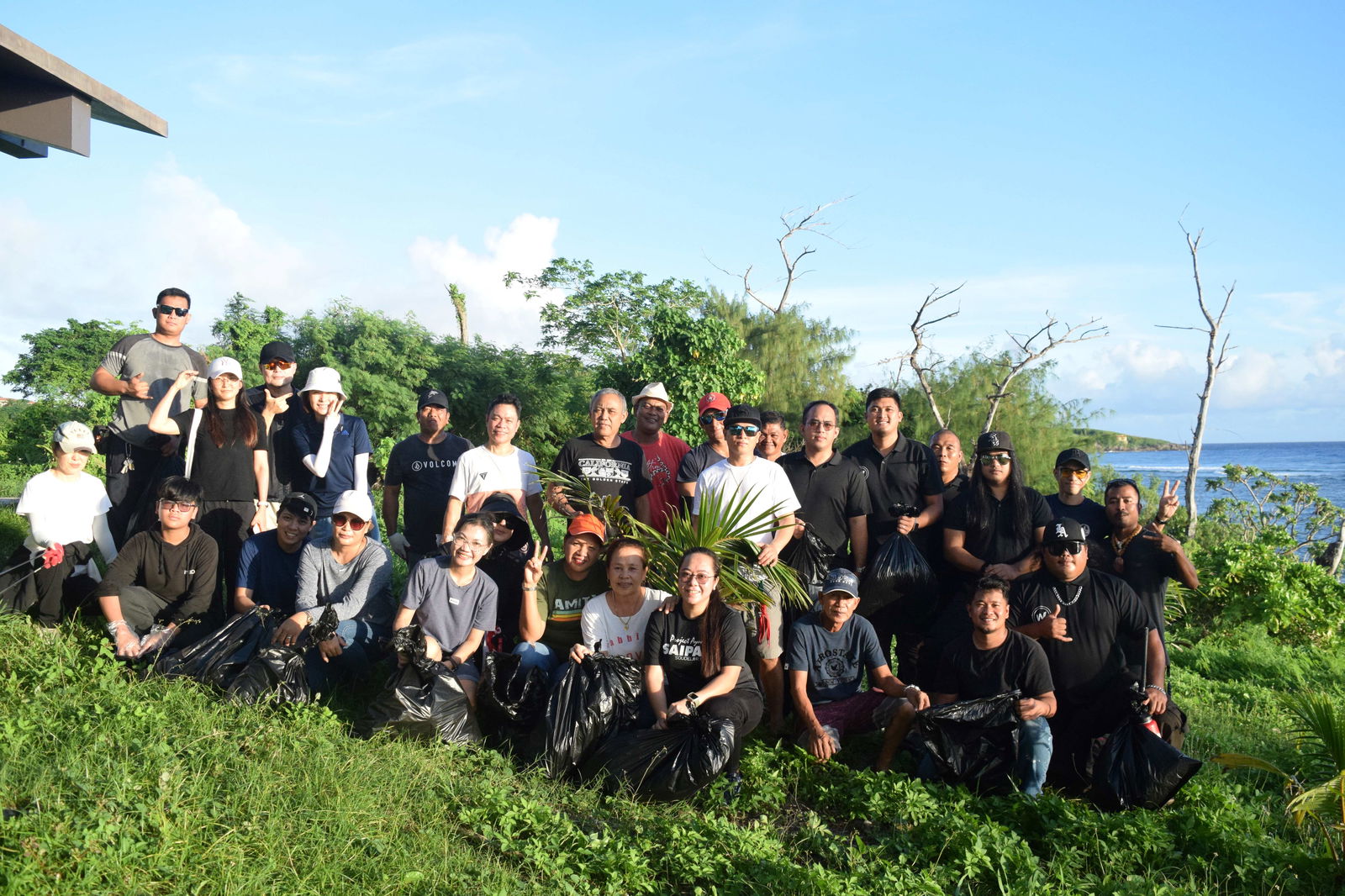 P& Corporation President Doyi Kim, second left, standing, backrow, and employees pose for photo after cleaning up the beach at Coral Ocean Resort on Saturday.