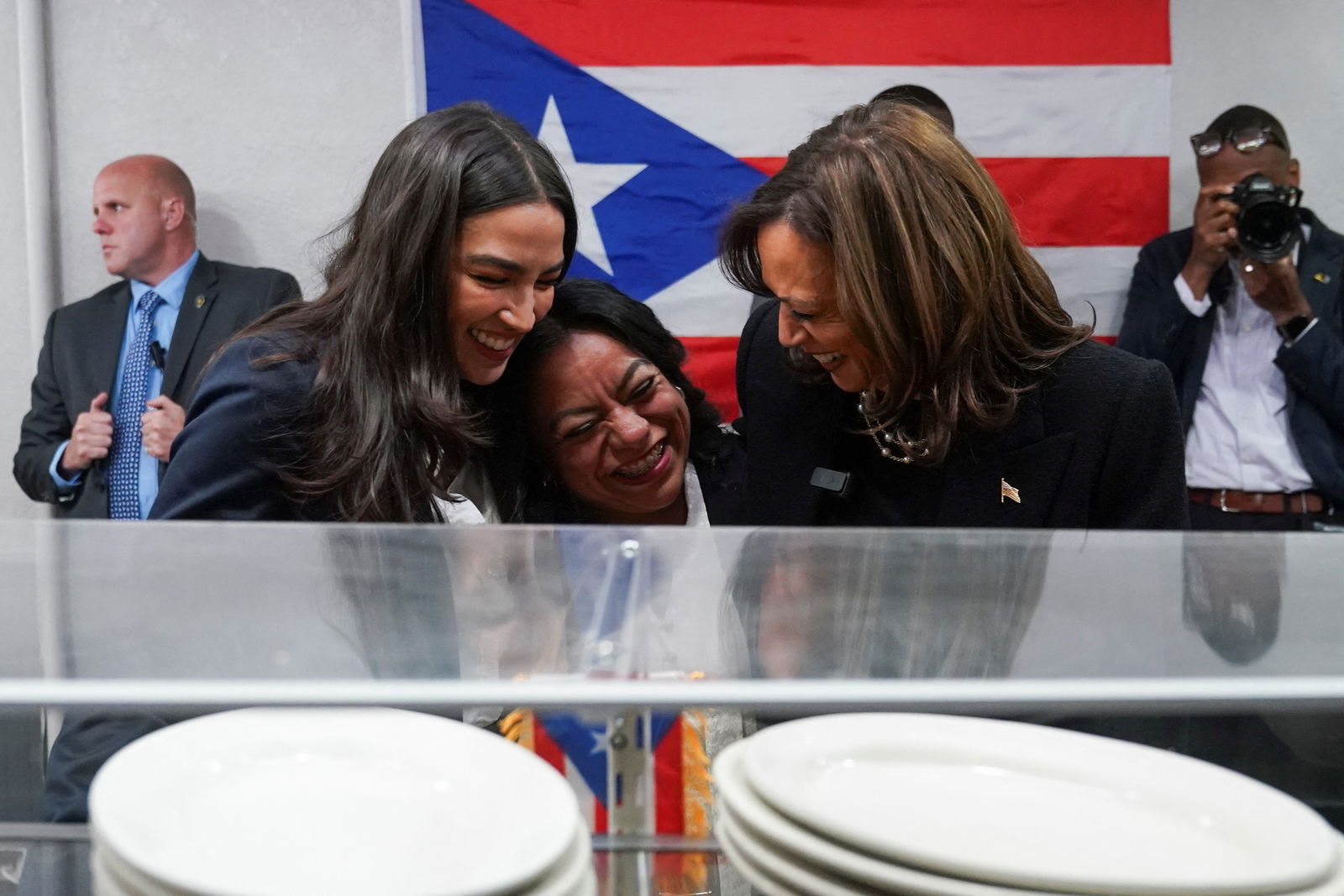 Democratic presidential nominee Kamala Harris, and U.S. Rep. Alexandria Ocasio-Cortez of New York, embrace Diana de la Rosa, owner of the Old San Juan Café, during a campaign stop in Reading, Pennsylvania, Nov. 4, 2024.
