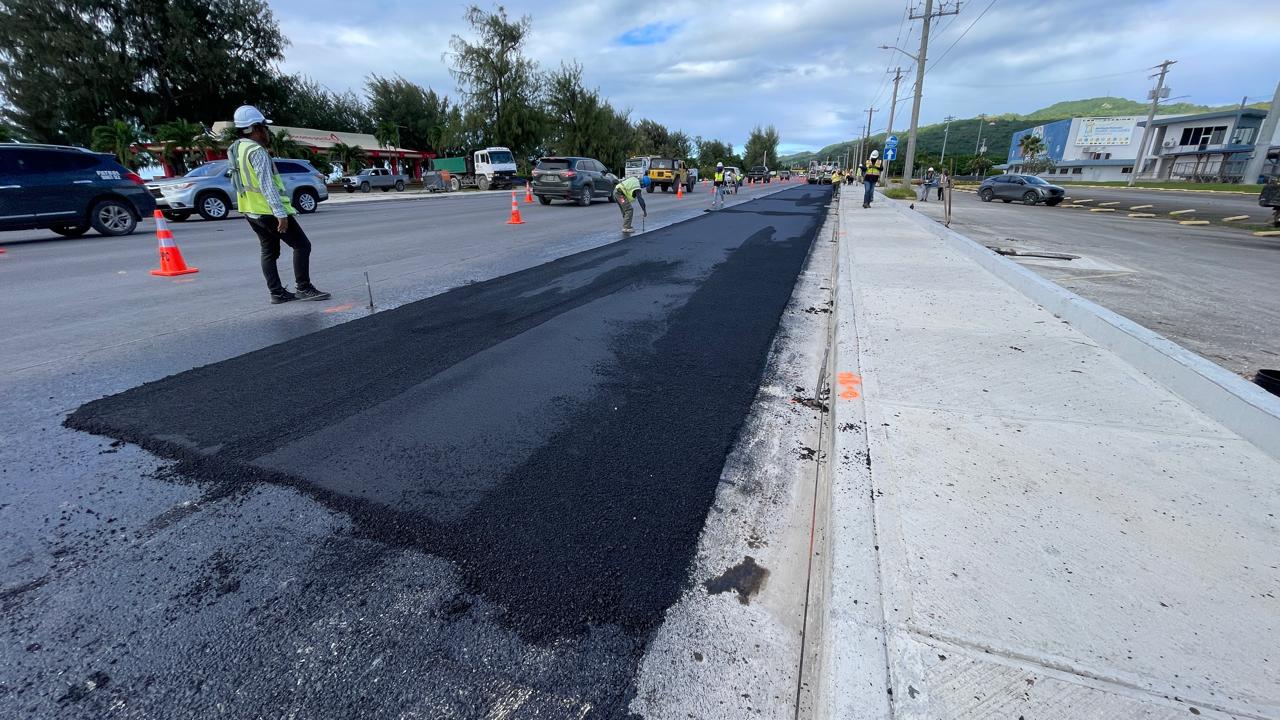 GPPC Inc. and Pacific Engineering Group & Services workers apply anti-skid material on a portion of Beach Road near the Ada Gym in Oleai on Monday.