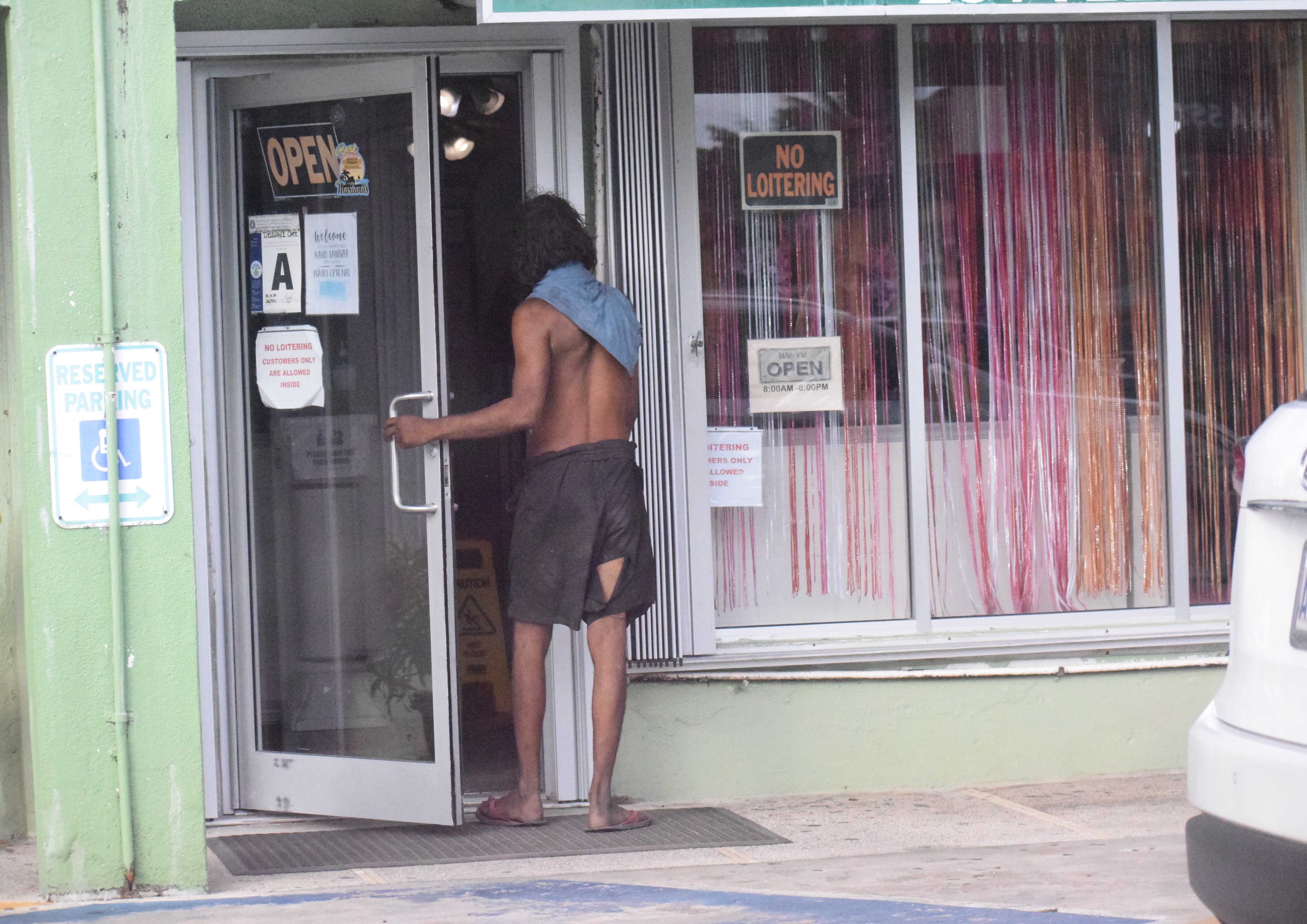 An individual, who is believed to be homeless, enters a business establishment in Garapan.