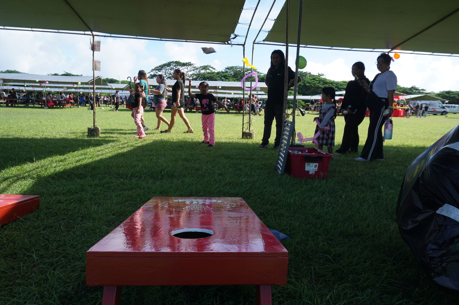 A young island resident tosses a bean bag into the air at a cornhole booth during Herman’s Modern Bakery’s Family Fun Day event. 