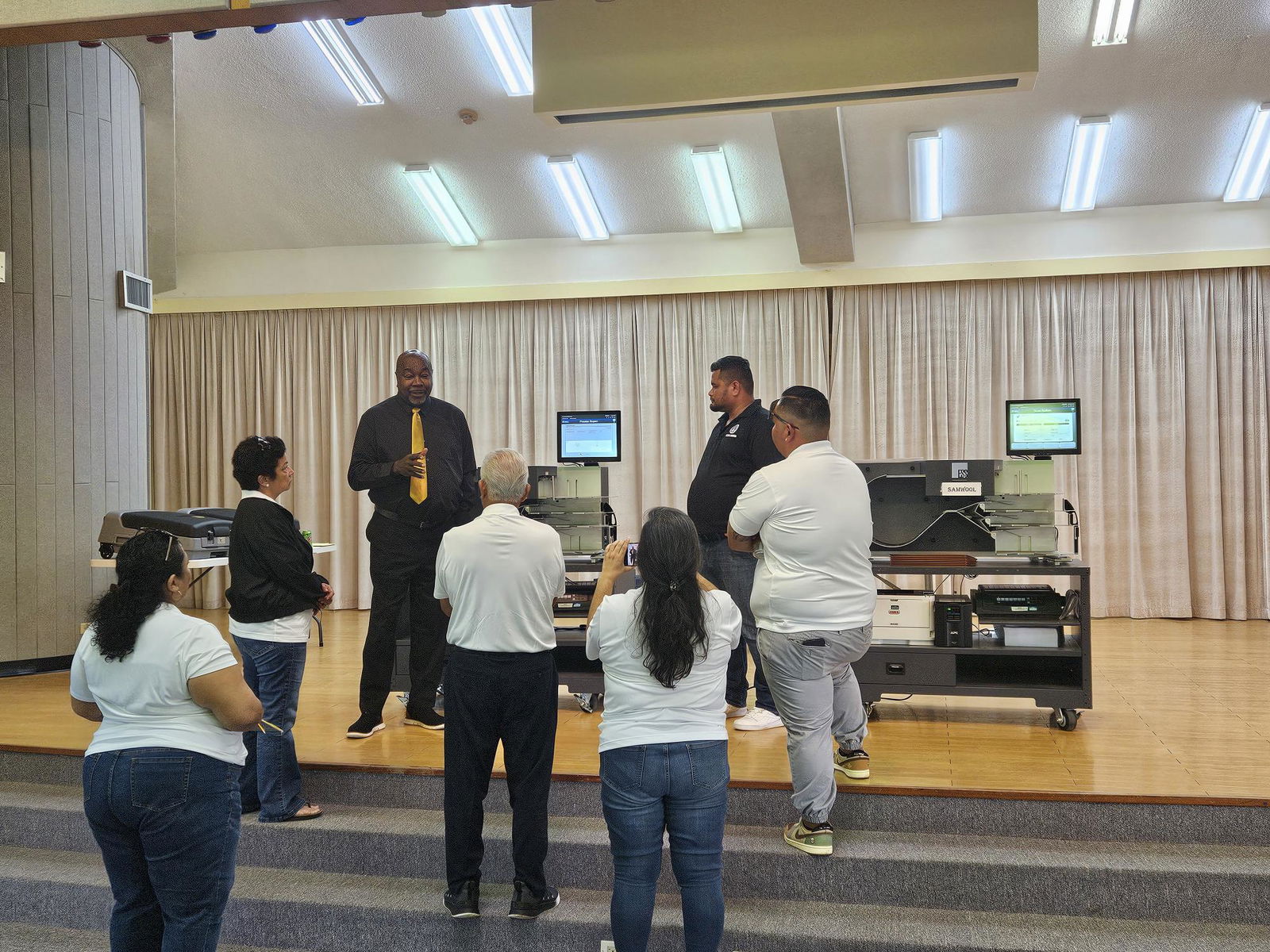Election System & Software executive Willie Wesley Jr. explains how the tabulation machine works as Commonwealth Election Commission staff listen at the multi-purpose center on Tuesday. The machine can read 100 ballots per minute.