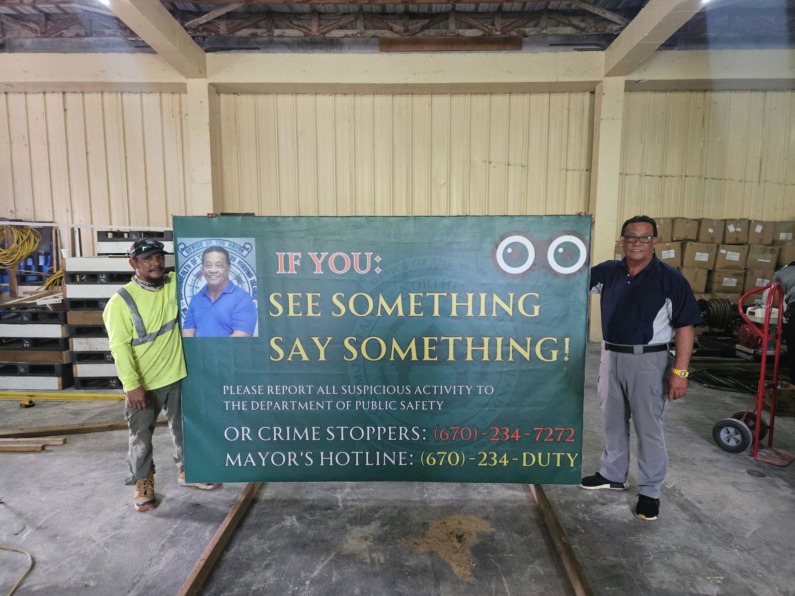 Saipan Mayor Ramon 'RB' Camacho, right, and a staff member stand beside a signboard intended for raising awareness about his safe-community initiatives.