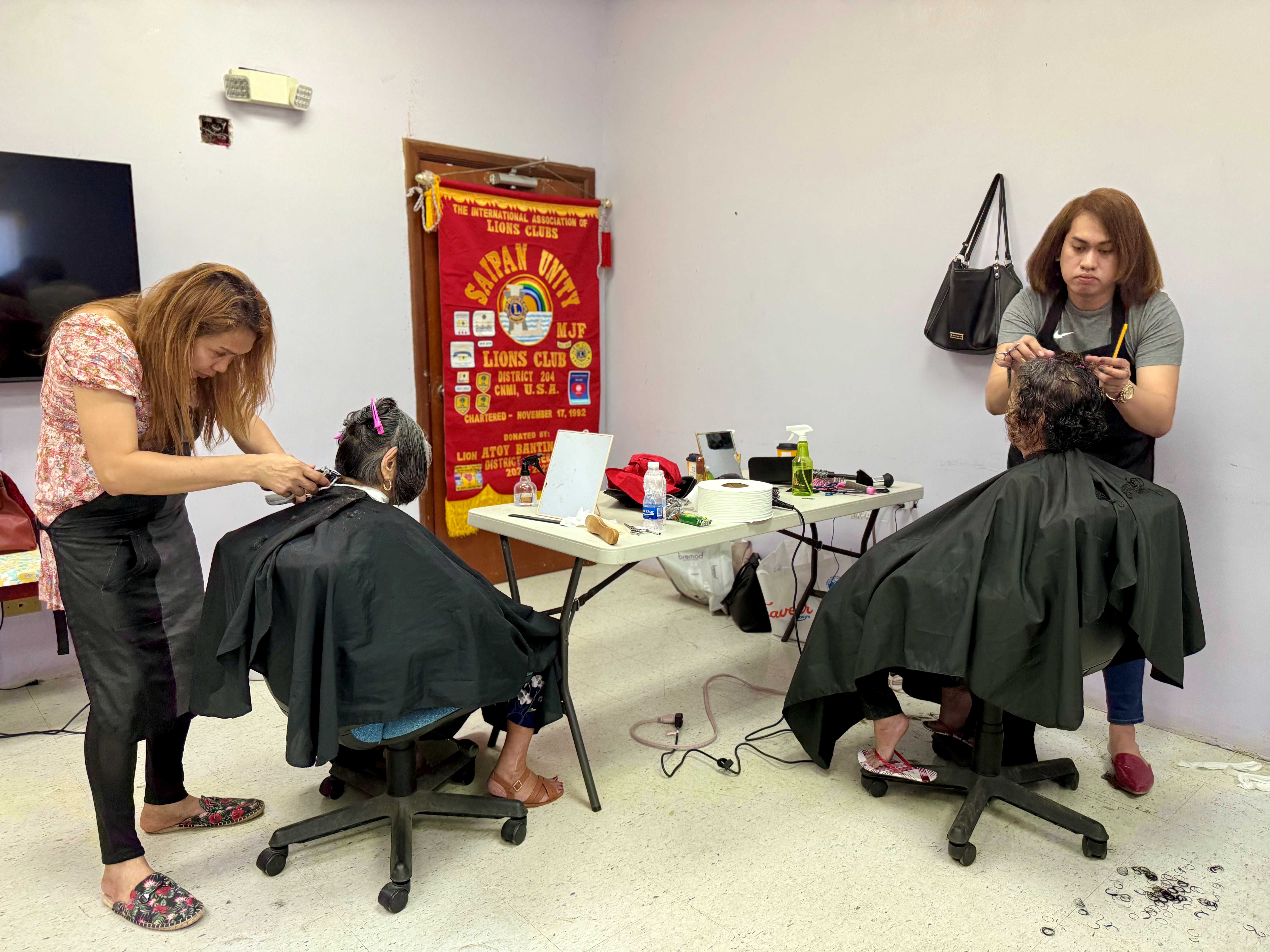 Beauticians Sharmaine Casquero, left, and Remyl Jhan Raymundo give senior citizens free haircuts during the Saipan Unity Lions Club’s “Manamko’ Makeover 2024” at the manamko’ center on Dec. 17, 2024.