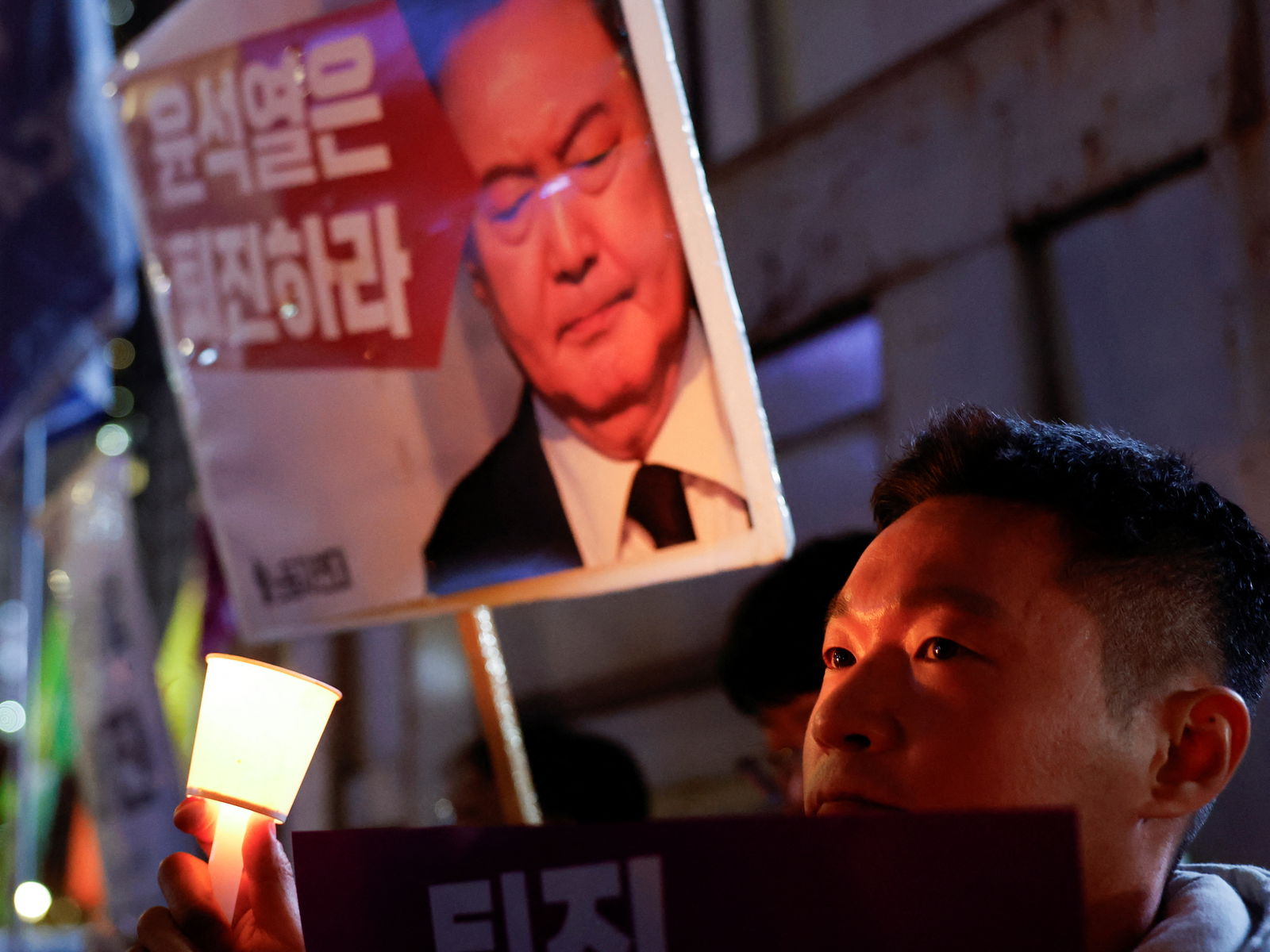 A man holds a placard as people attend a candlelight vigil condemning South Korean President Yoon Suk Yeol's surprise declaration of martial law, which was reversed hours later, and to call for his resignation, in Seoul, South Korea, Dec. 4, 2024.