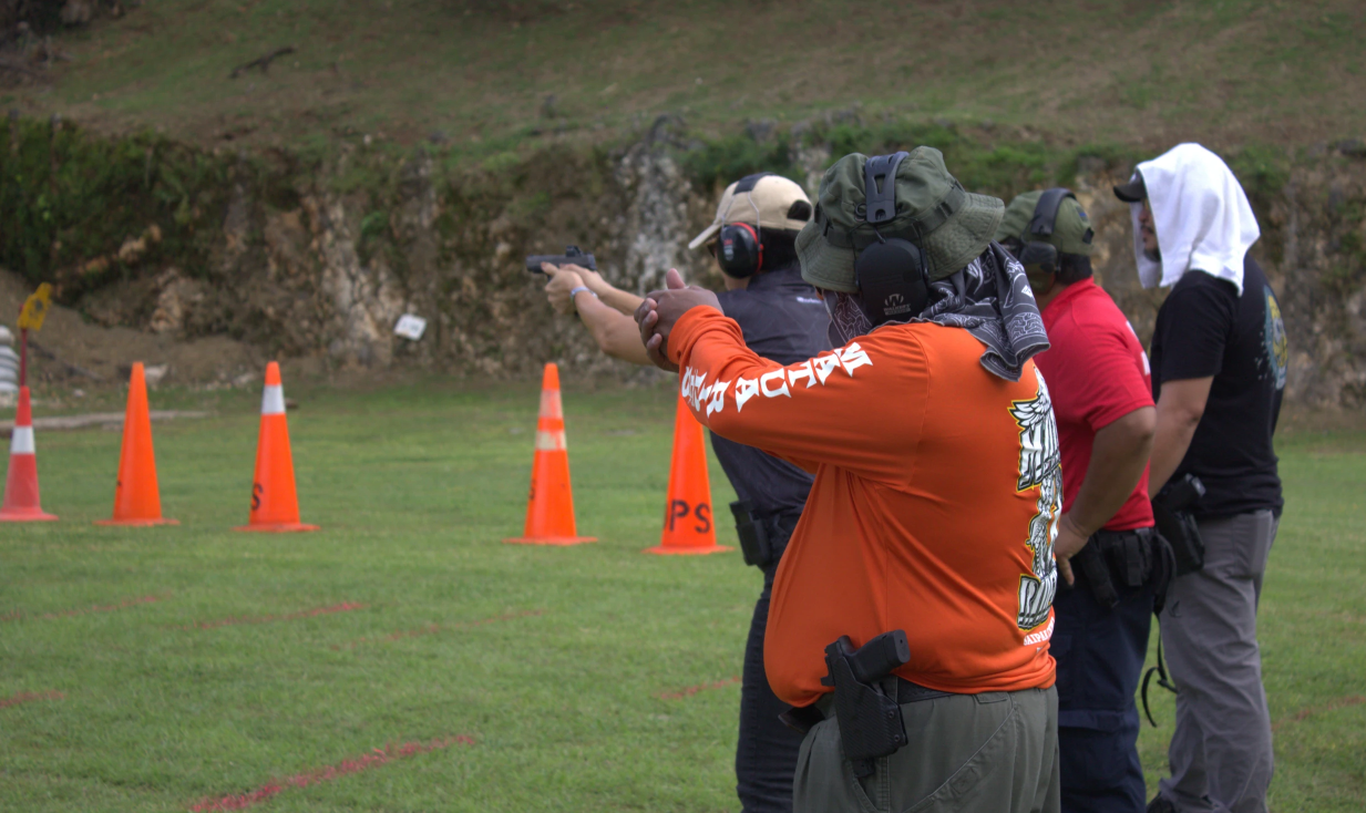 First-time Competitor Judge Teresa Kim-Tenorio shoots at her target while Deputy Marshall III Jesus Santos observes and provides encouragement at the Judiciary Firearms Competition.