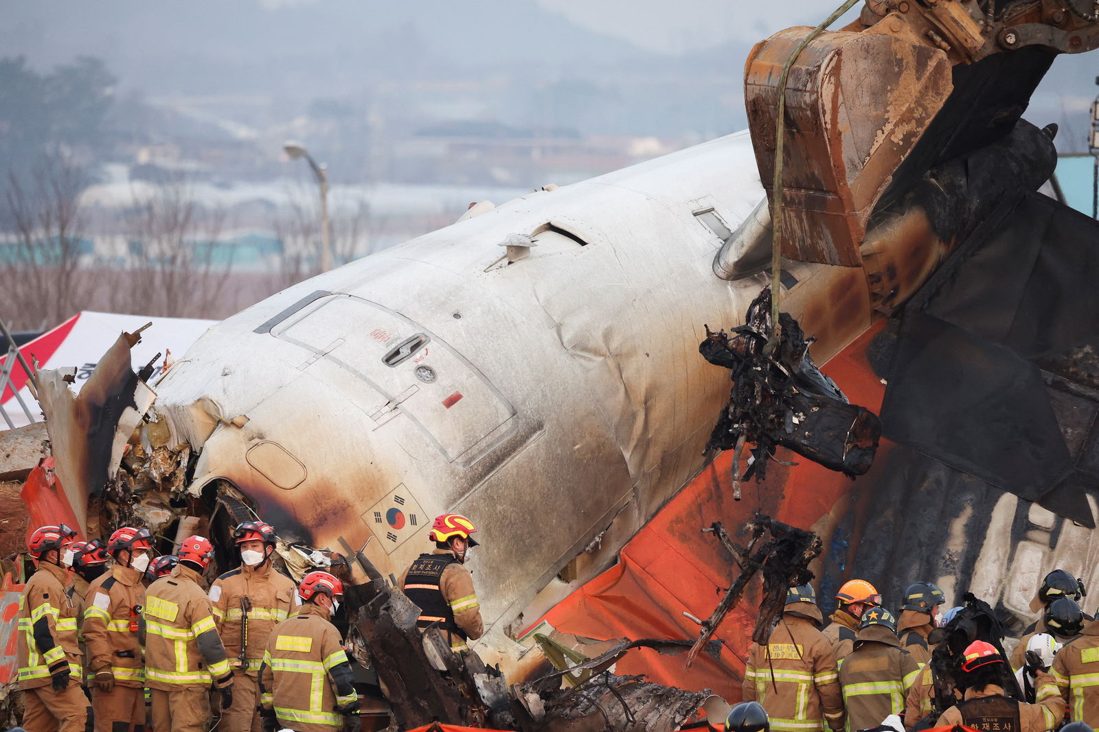 An excavator is used to lift burnt chairs from the wreckage of an aircraft that crashed after it went off the runway at Muan International Airport, in Muan, South Korea, Dec. 29, 2024.