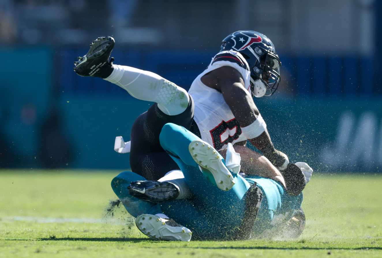 Jacksonville Jaguars quarterback Trevor Lawrence (16) is hit by Houston Texans linebacker Azeez Al-Shaair (0) as he slides down in the second quarter in the second quarter at EverBank Stadium in Jacksonville, Florida, Dec. 1, 2024.