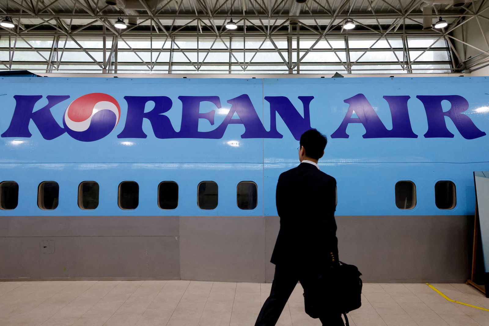 A man walks next to the logo of Korean Air airlines during an organized media tour, at the company's Cabin Crew Training Center in Seoul, South Korea, June 27, 2024.