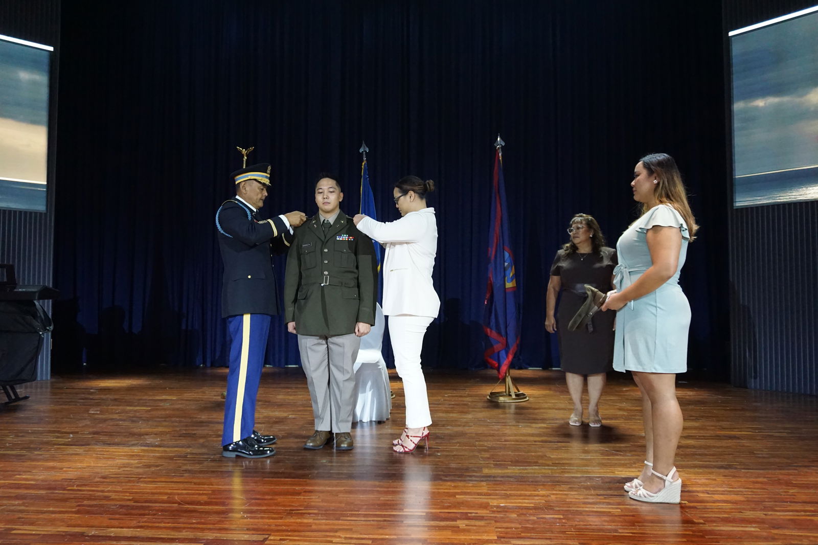 Franklin Babauta Jr. stands at attention as his father, Franklin Babauta Sr., left, and sister, Francine Babauta, right, pin his officer rank on him. His sister, Kolina Babauta, far right, waits to place his cap on his head. His mother, Sen. Celina Babauta, is in the background.