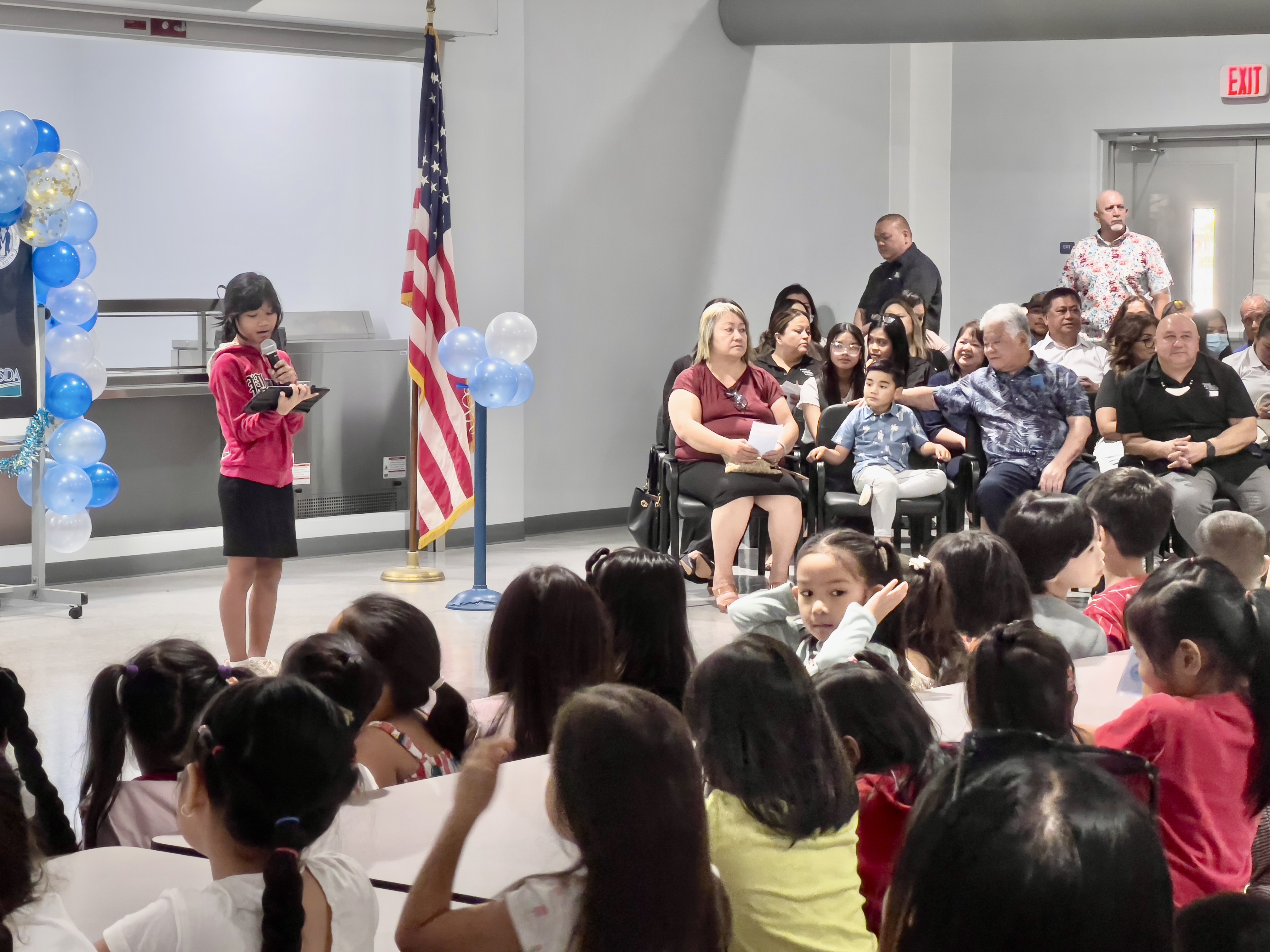 A Garapan Elementary School student, standing left, performs a song number as part of the student-led celebration in their new cafeteria.