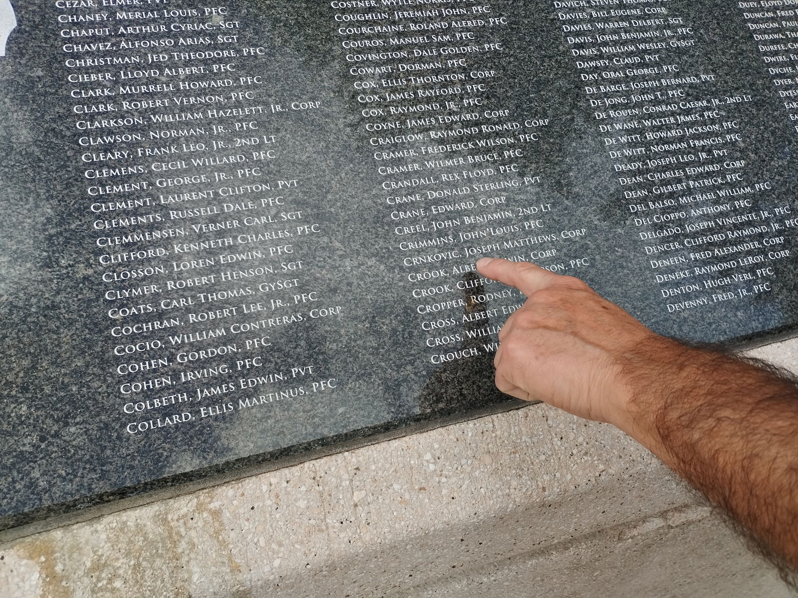 Ken Sava points to the name "Crnkovic, Joseph Matthews CORP" on the plaque at American Memorial Park's Court of Honor.
