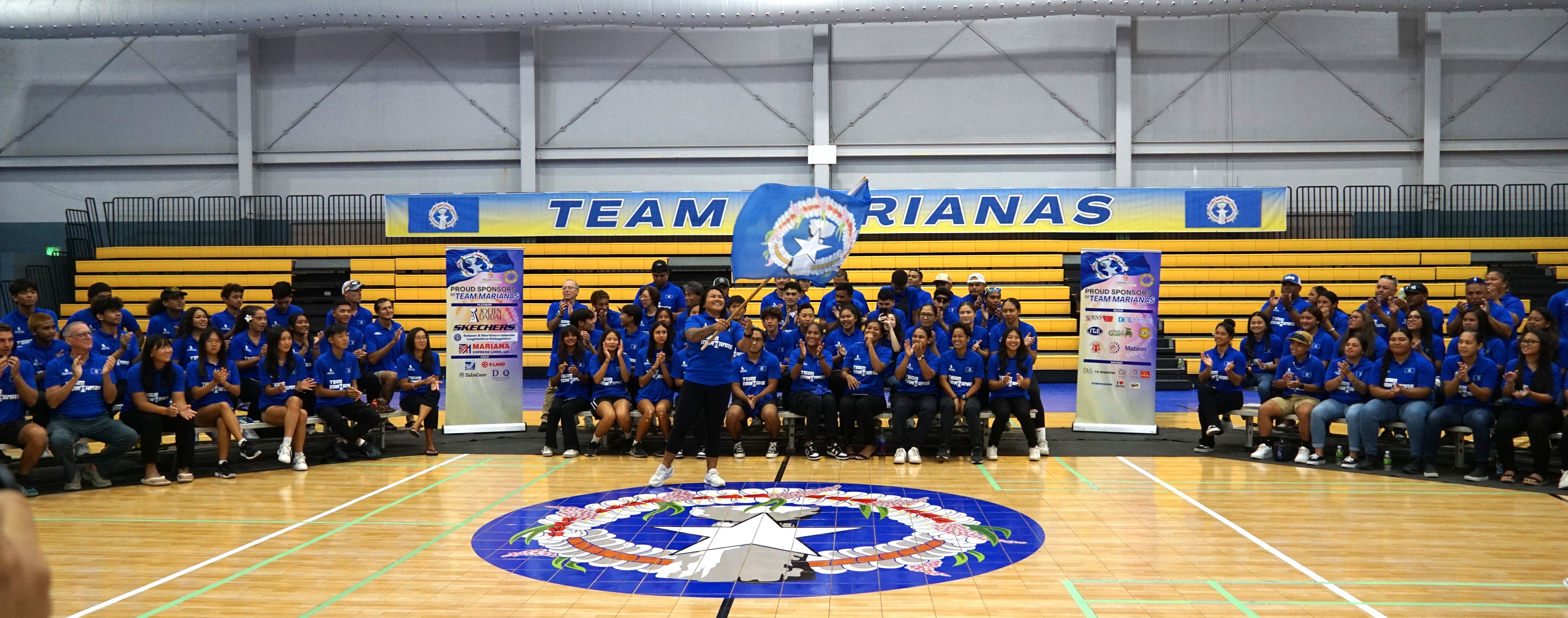 During the sendoff ceremony for the 2024 Micronesia Games at the Ada gym, Antonette Labausa, center, waves the NMI flag after being selected as Team Marianas’ flagbearer.
