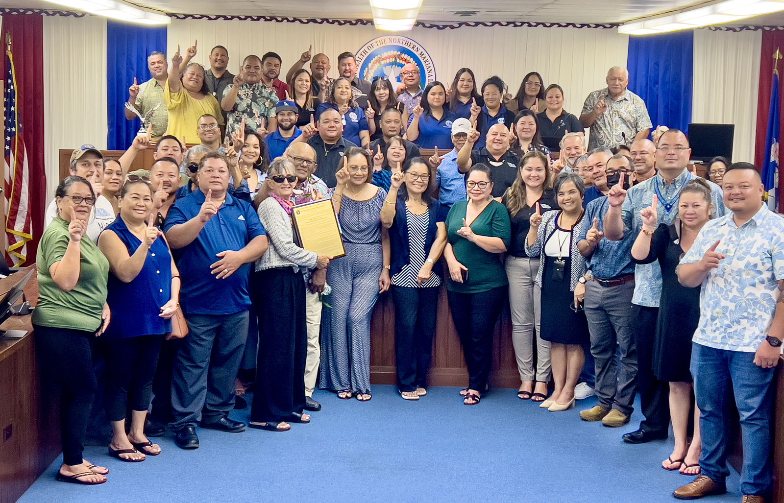 Former Board of Education Chairman Herman A. Atalig, fifth left, front row, was honored Monday afternoon by the House of Representatives for his significant contributions in public education on Rota and the CNMI. Holding the commemorative resolution is his lifetime mentor, educator and former BOE member D. Tanya King. Also in photo are BOE Chair Gregory Pat Borja, BOE Vice Chair Maisie B. Tenorio, Commissioner of Education Dr. Lawrence F. Camacho, lawmakers and education officials. They are flashing the number 1 sign to signify “Students First,” which is the motto of the Public School System.PSS photo