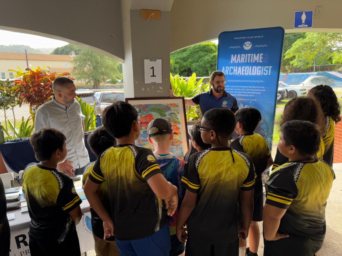 Steve McKagan of NOAA National Marine Fisheries Service, rights, speaks to school MYWAVE Club members the Marianas Tourism Education Council Tourism Summit on Jan. 24, 2025, at Garapan Central Park in Saipan.