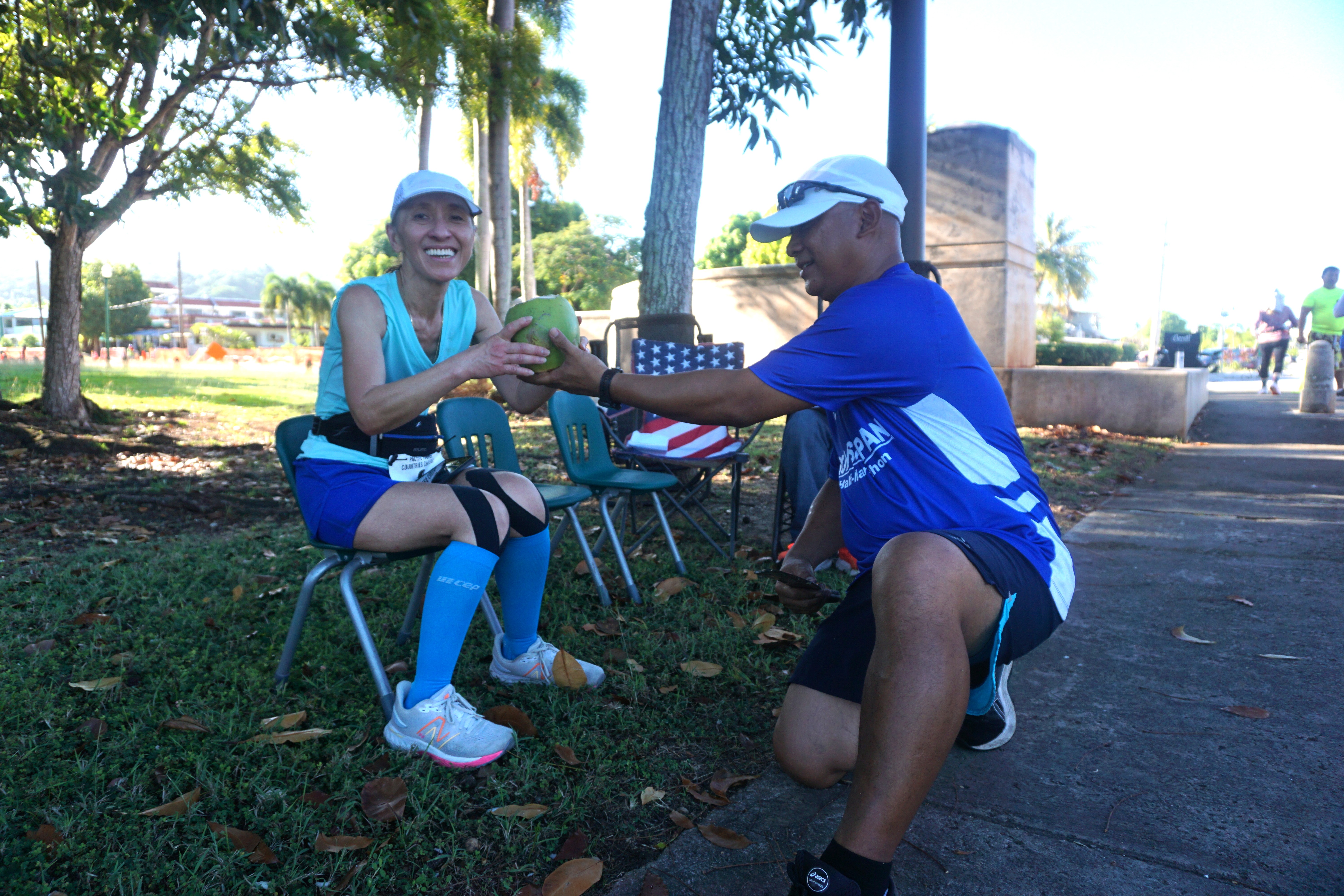 Run Saipan’s Robin Sapong hands a coconut to a runner who completed the marathon.