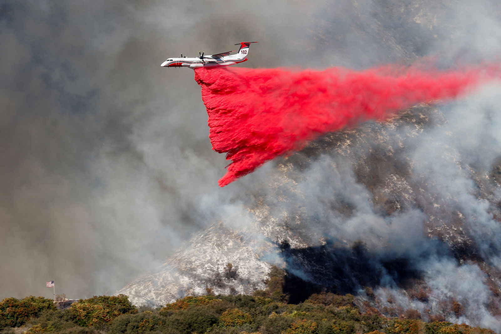 A plane makes a drop as smoke billows from the Palisades Fire at the Mandeville Canyon, in Los Angeles, California, Jan. 11, 2025.