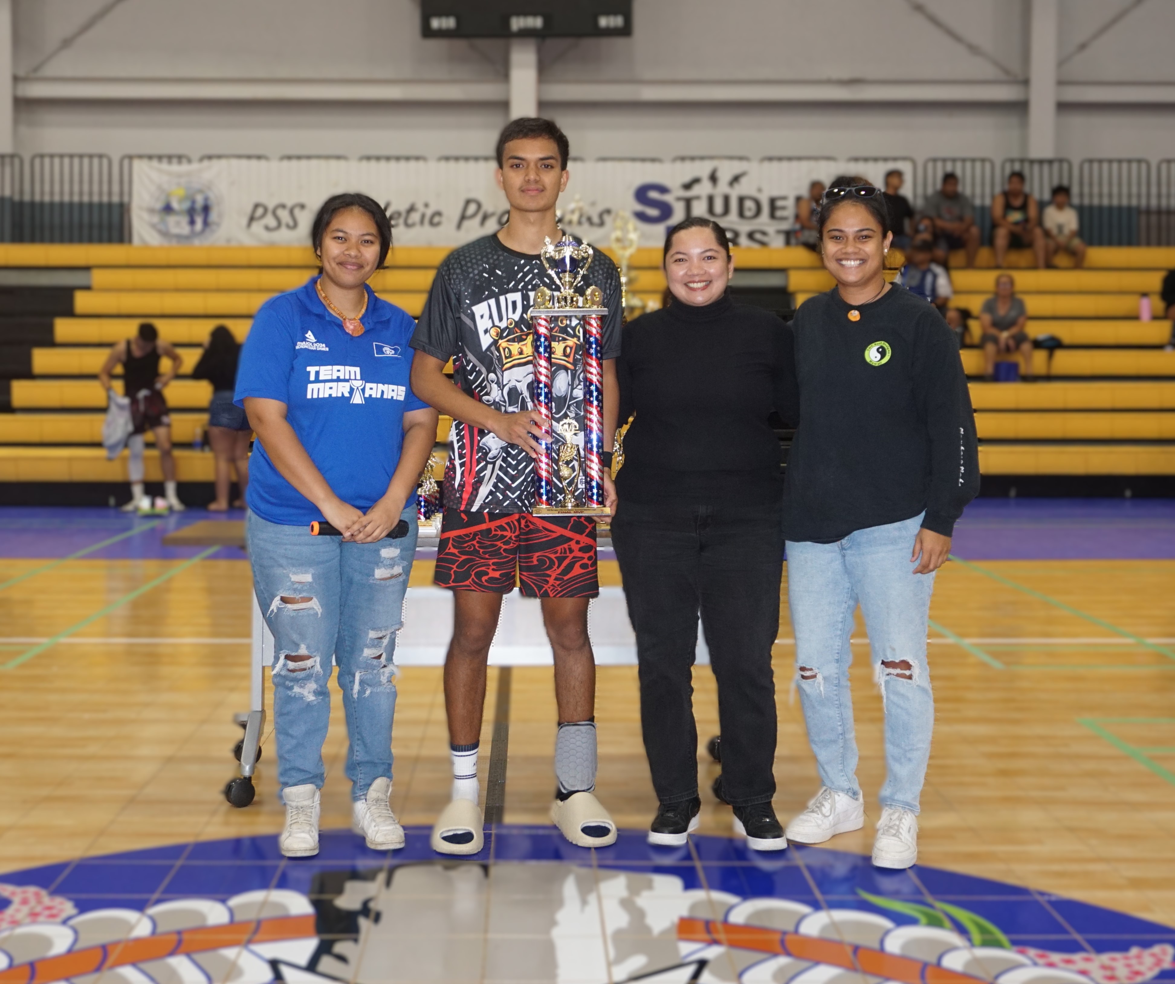 Marpac’s Chioni Dela Cruz poses with the Finals MVP award alongside officials of the Northern Mariana Islands Basketball Federation.
