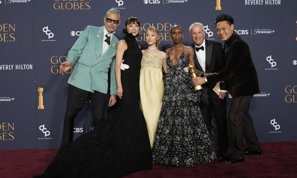 Jeff Goldblum, from left, Michelle Yeoh, Ariana Grande, Cynthia Erivo, Marc Platt and Jon M. Chu pose with the award for cinematic and box office achievement for “Wicked” in the press room during the 82nd Golden Globes on Sunday, Jan. 5, 2025 at the Beverly Hilton in Beverly Hills, Calif.