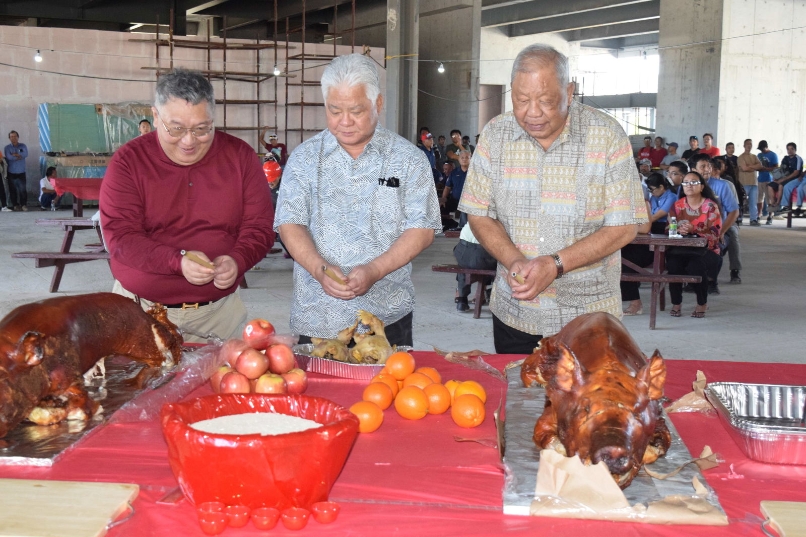 Gov. Arnold I. Palacios, center, and Lt. Gov. David M. Apatang, right, join WinWin Way Construction Director Jim HS Kan in the ceremonial blessing of food.