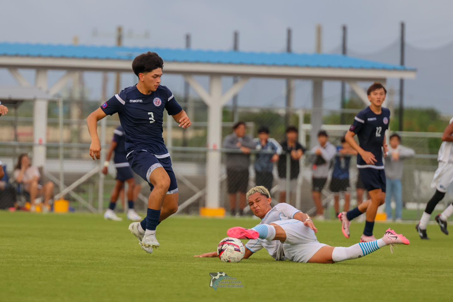 The NMI's Andrew Sablan slides to deny the entry pass from Guam during a 2024 U20 Men’s Marianas Football Cup match at the NMI Soccer Training Center in Koblerville.