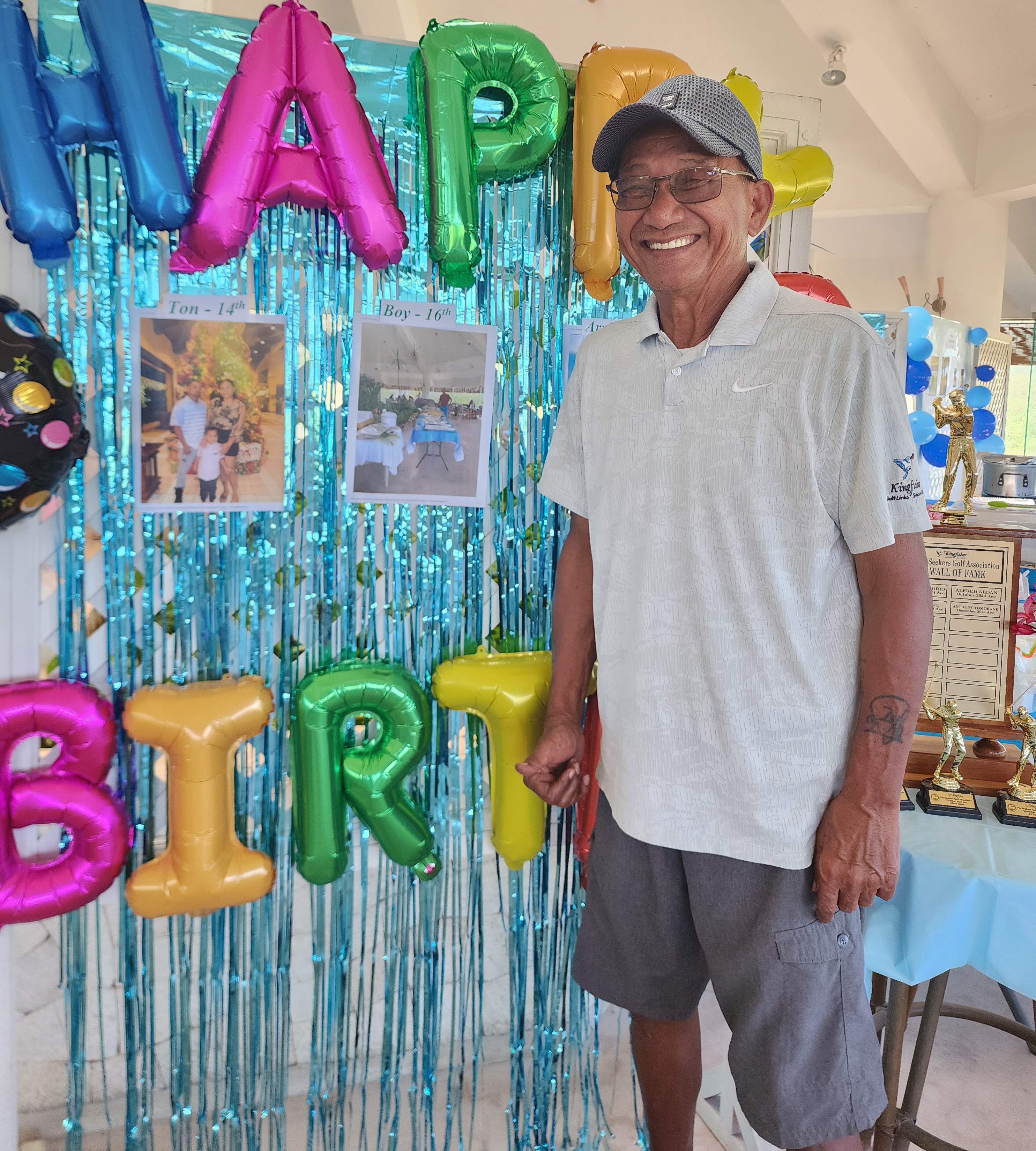 Grina Mizutani, a co-founder of Familia Golf Association, poses at the birthday backdrop prepared for birthday celebrants, who included his golf partner, the late Anthony S. Camacho Jr.