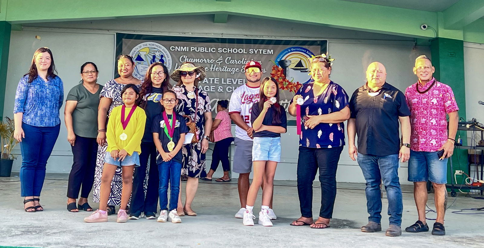 The winners of the elementary school poster/drawing contest pose on stage with Commissioner of Education Dr. Lawrence F. Camacho and the organizing committee members.
