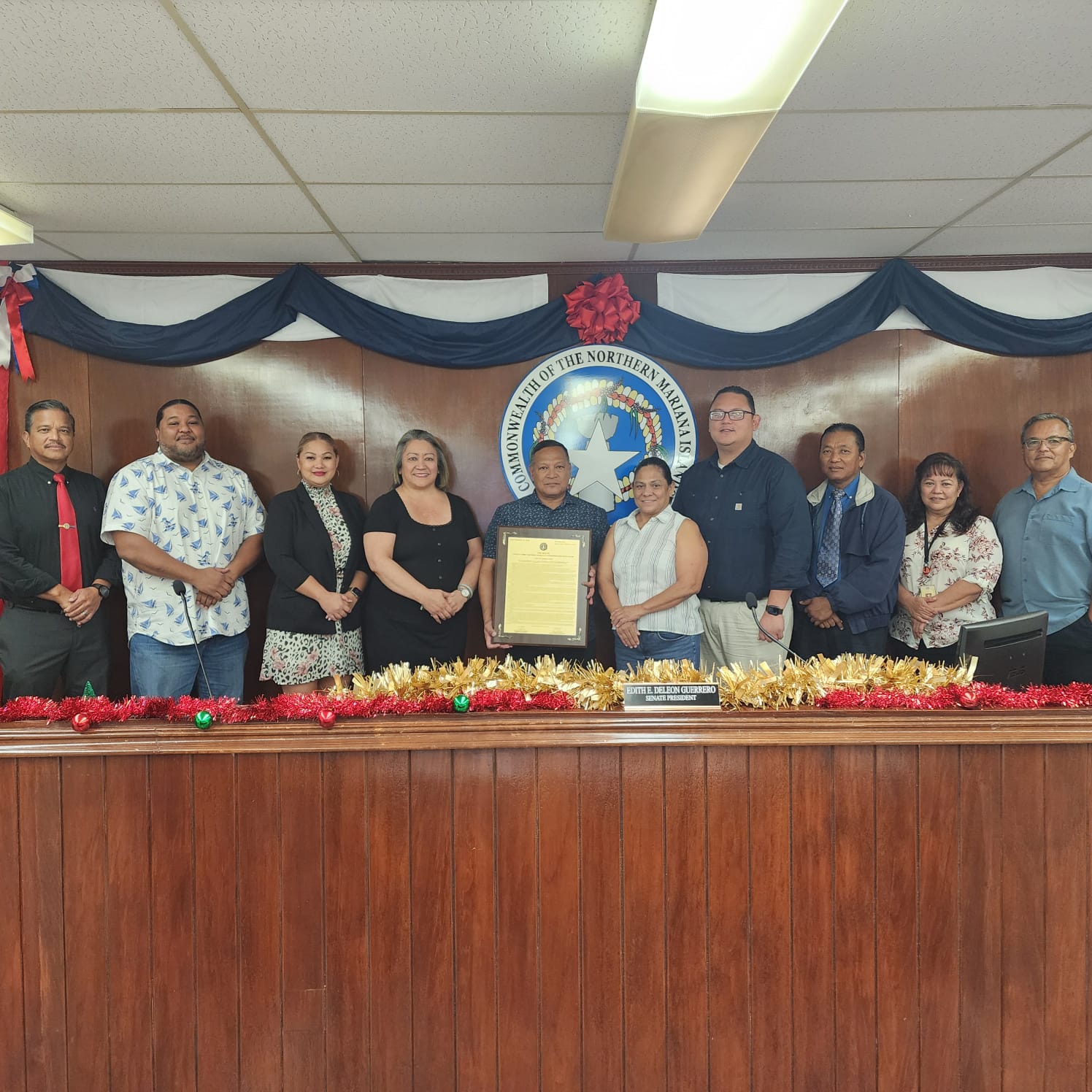 The special assistant for military affairs and the chief of the Commonwealth Bureau of Military Affairs, retired U.S. Army Lt. Col. Edward C. Camacho, center, poses for a photo with senators and the CBMA grants budget officer, Annie Santos, fifth right, during the presentation of Senate Resolution 23-34 on Friday. 