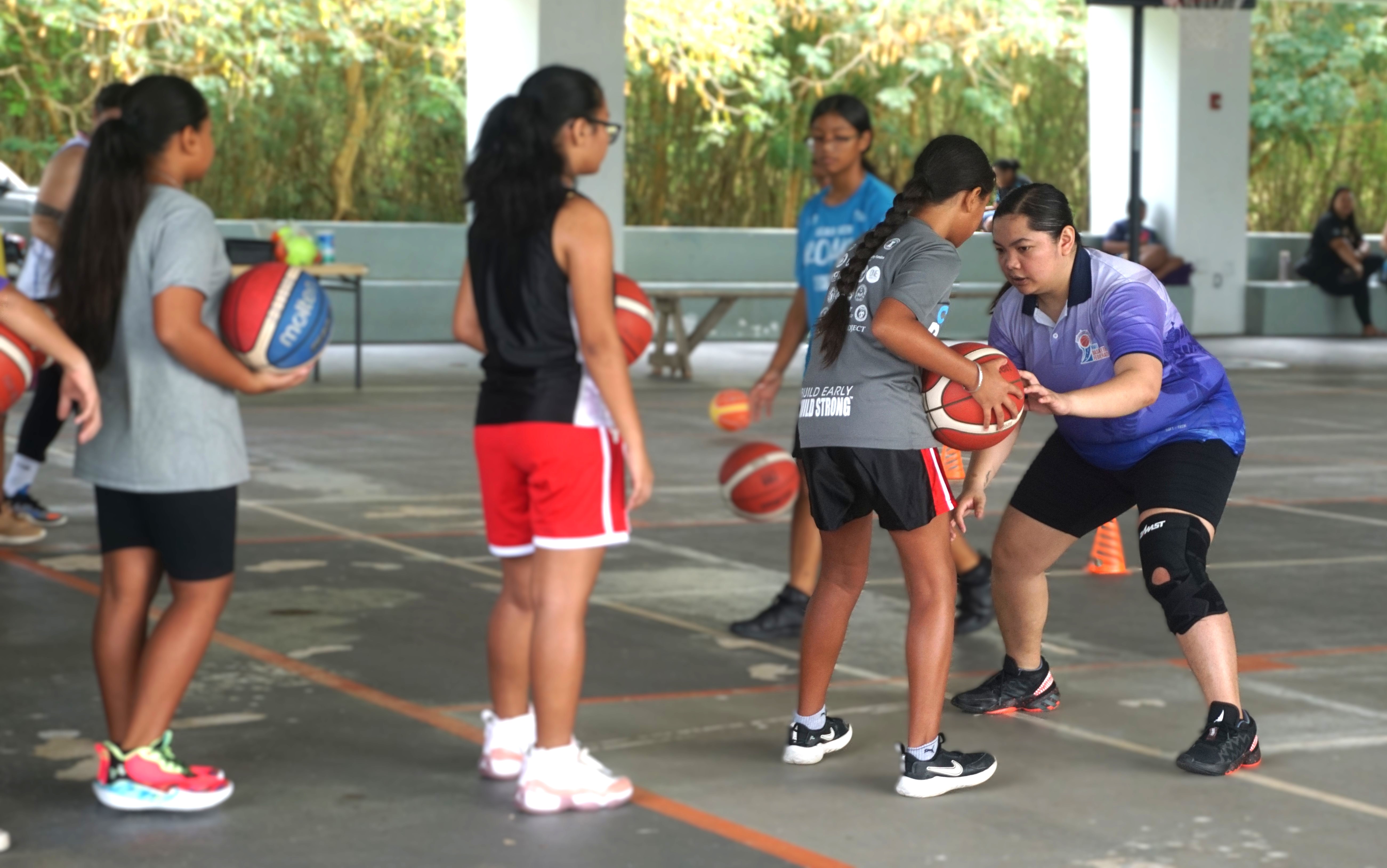 Marlene Lumabi teaches a participant the triple threat technique during the I Am Her basketball camp at the Koblerville gym on Saturday.